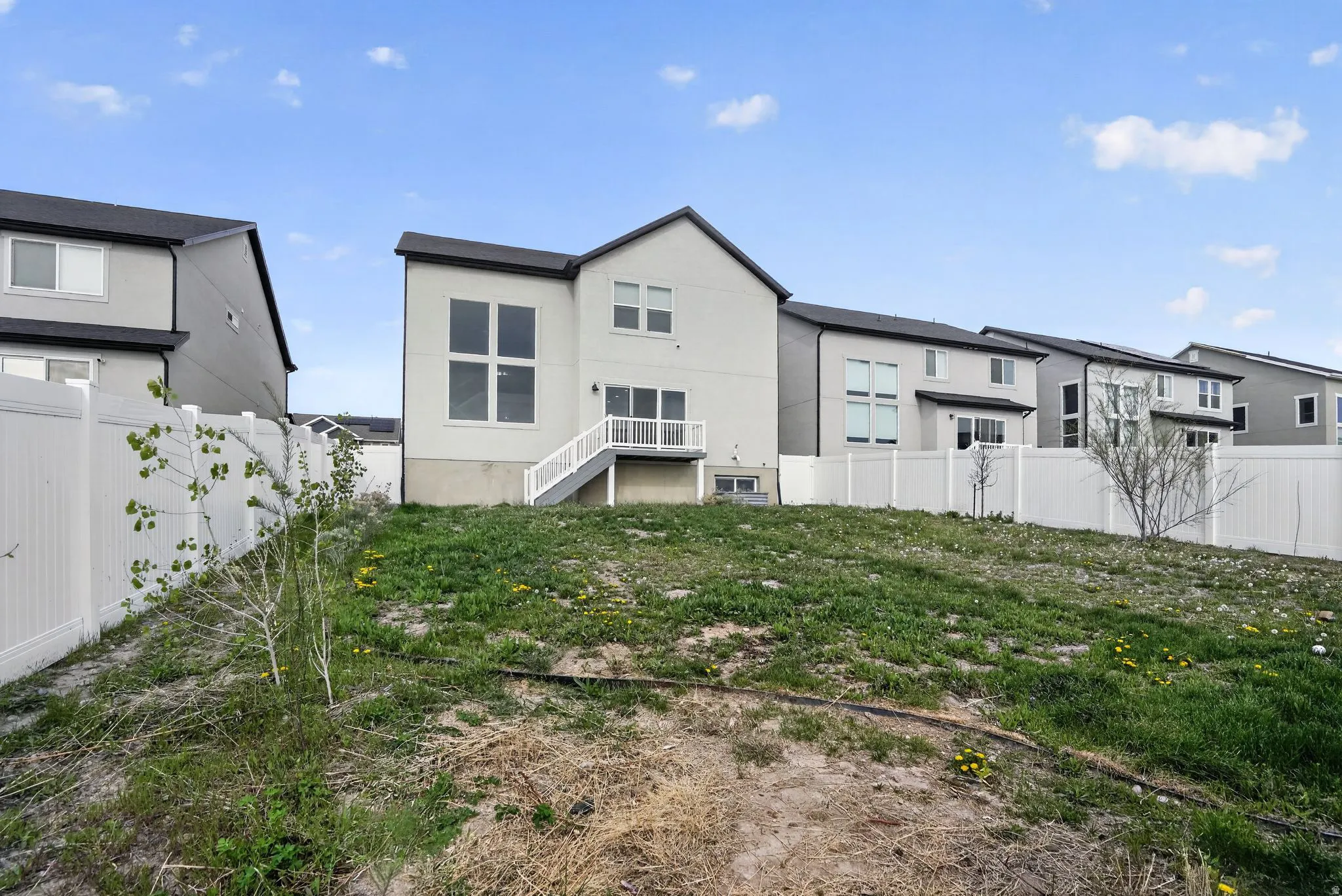 Back of property with a fenced backyard and stucco siding