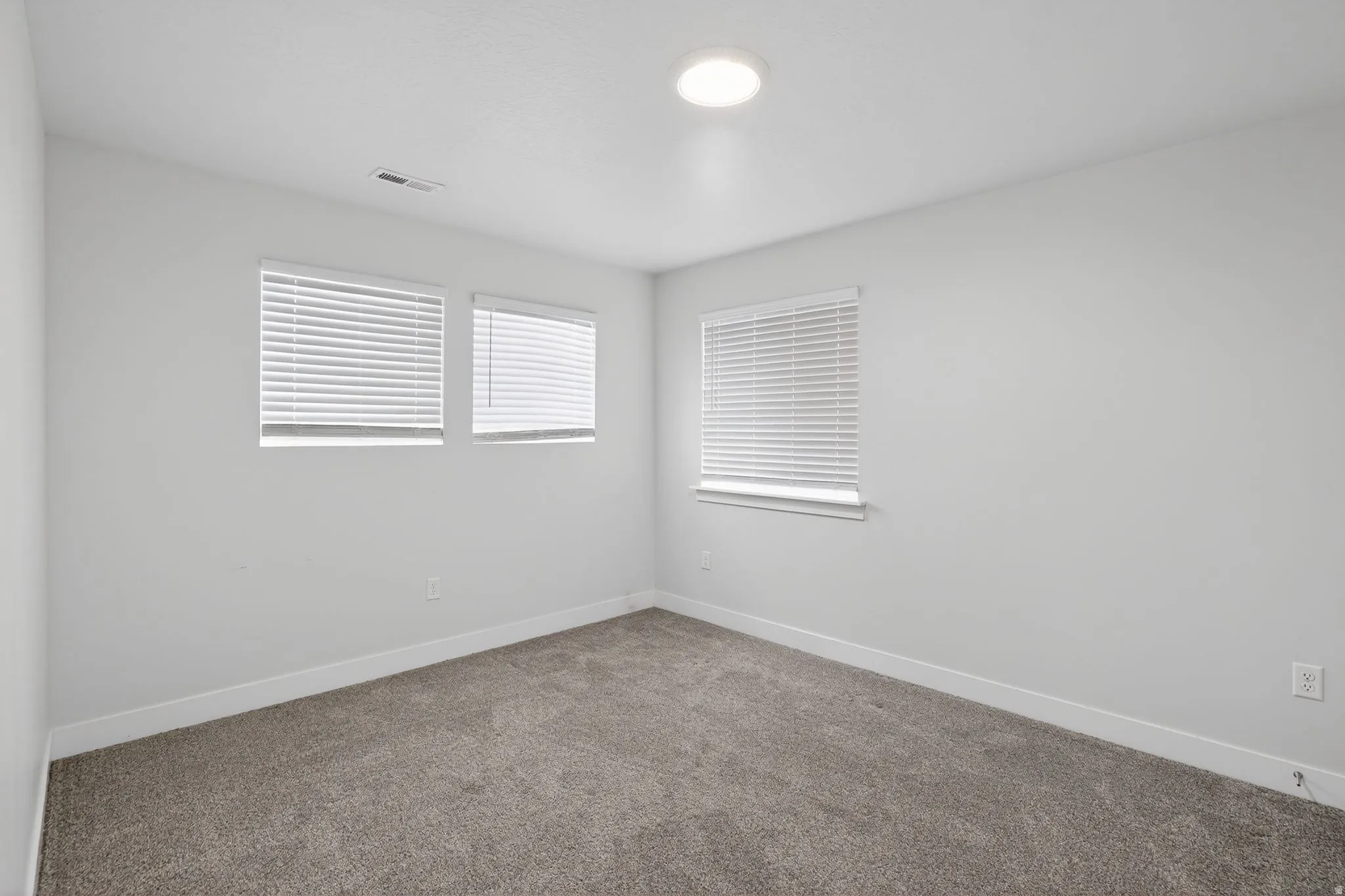 Carpeted spare room featuring baseboards