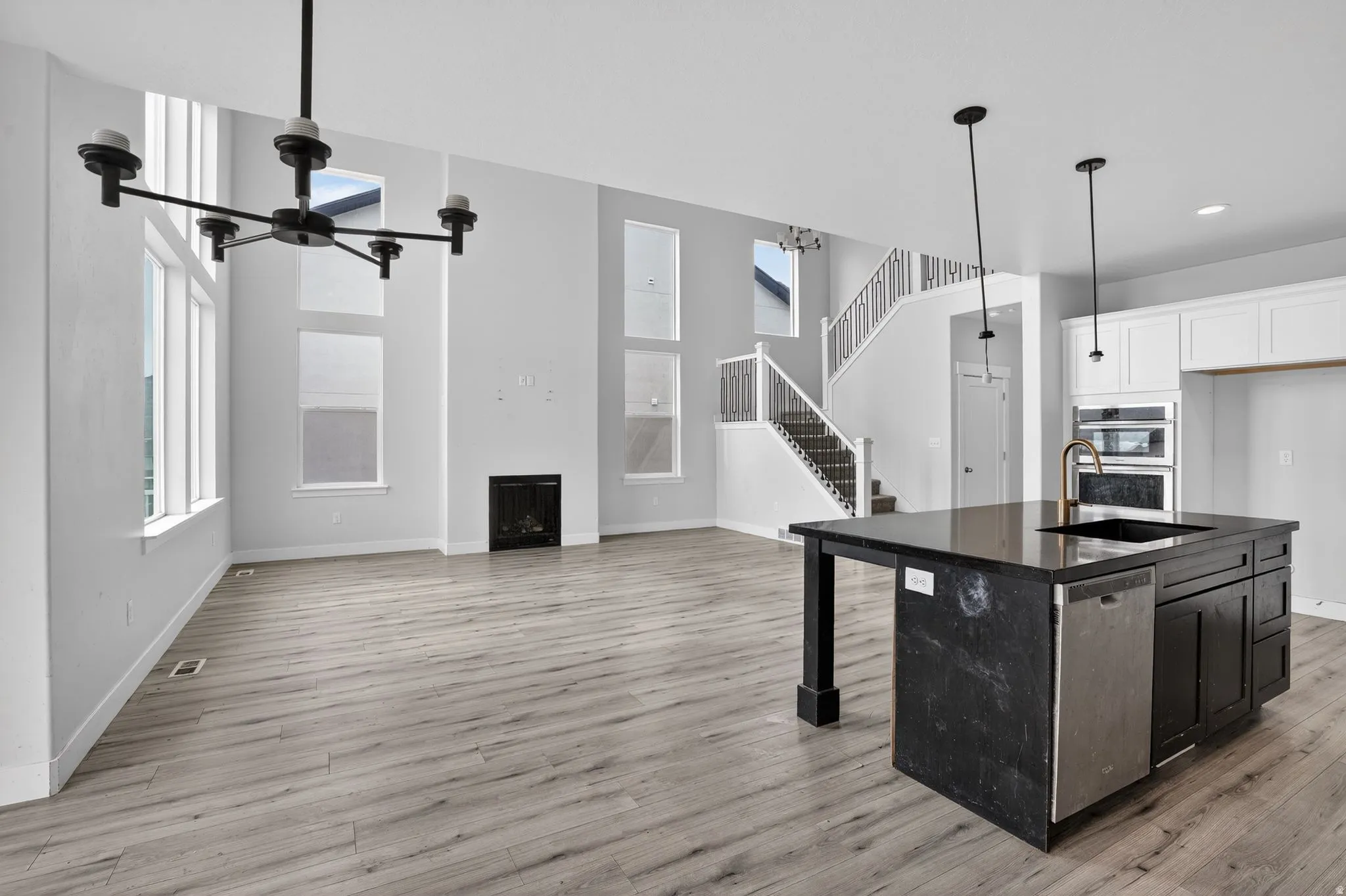 Kitchen with a fireplace, a high ceiling, a kitchen island with sink, stainless steel appliances, and open floor plan