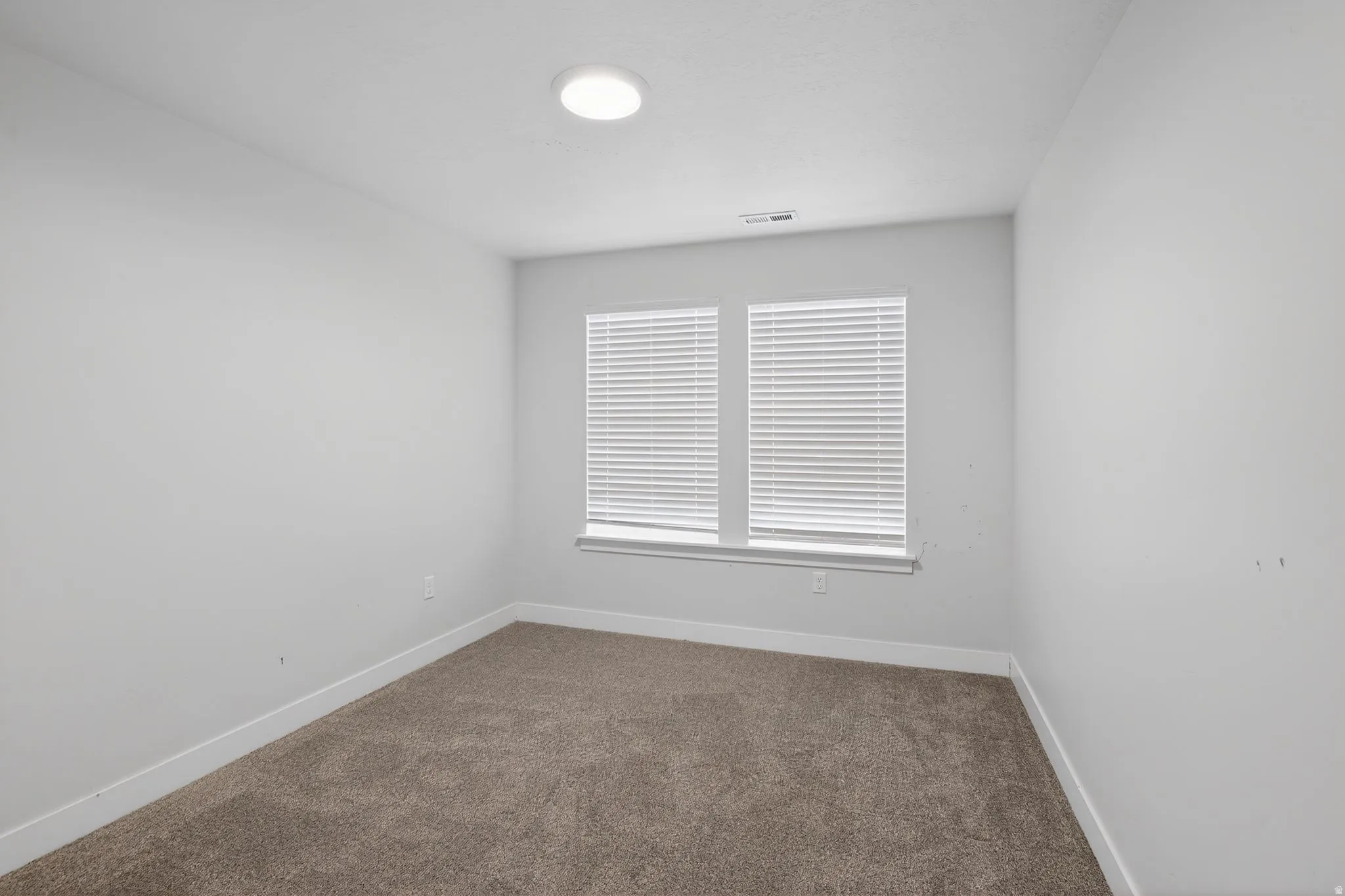 Spare room featuring dark carpet and baseboards