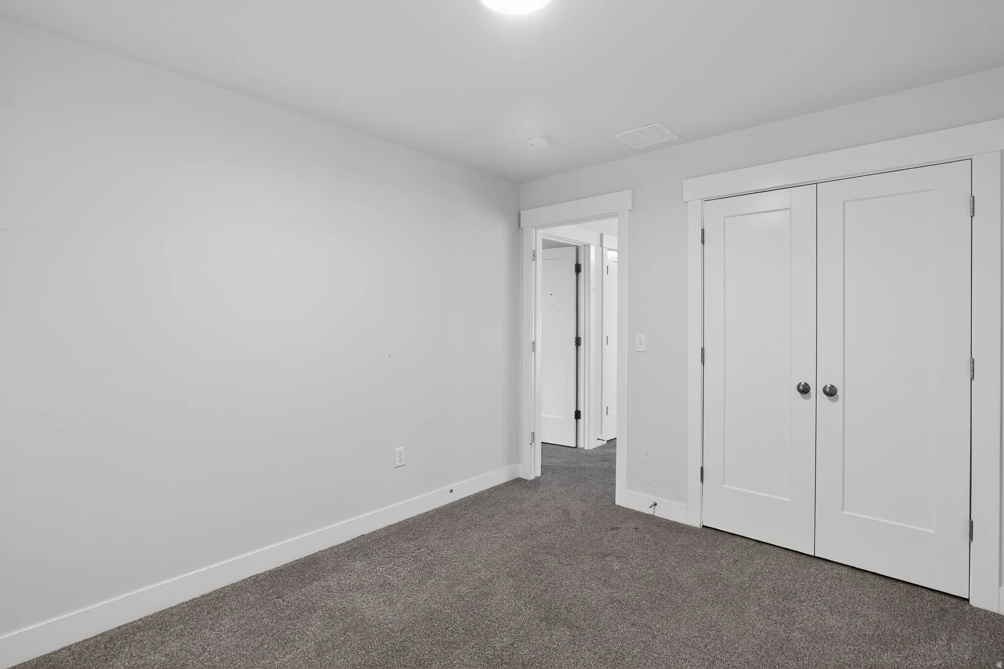 Unfurnished bedroom with dark carpet and a closet