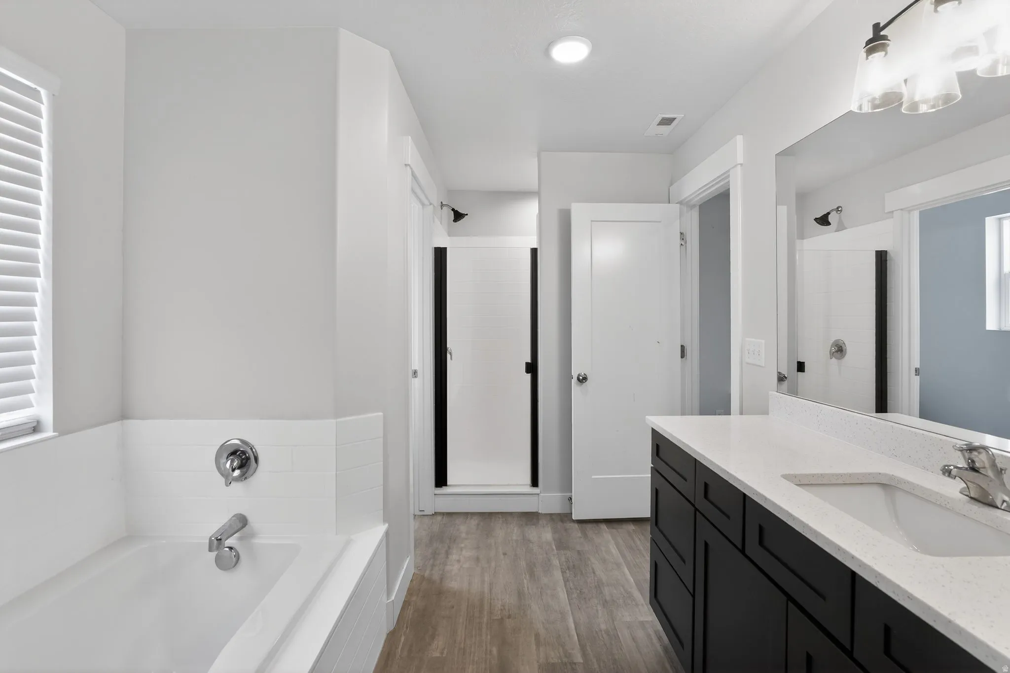 Full bathroom with vanity, a garden tub, dark wood finished floors, and a shower stall