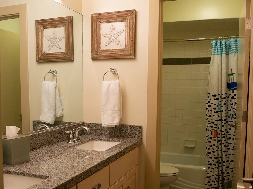 Bathroom with double vanity, dark tile flooring, and shower / bath combination.