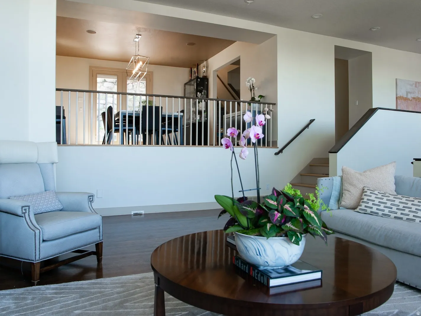 Open concept living area featuring dark wood-finish flooring, a white painted half wall with balusters to display dining room.