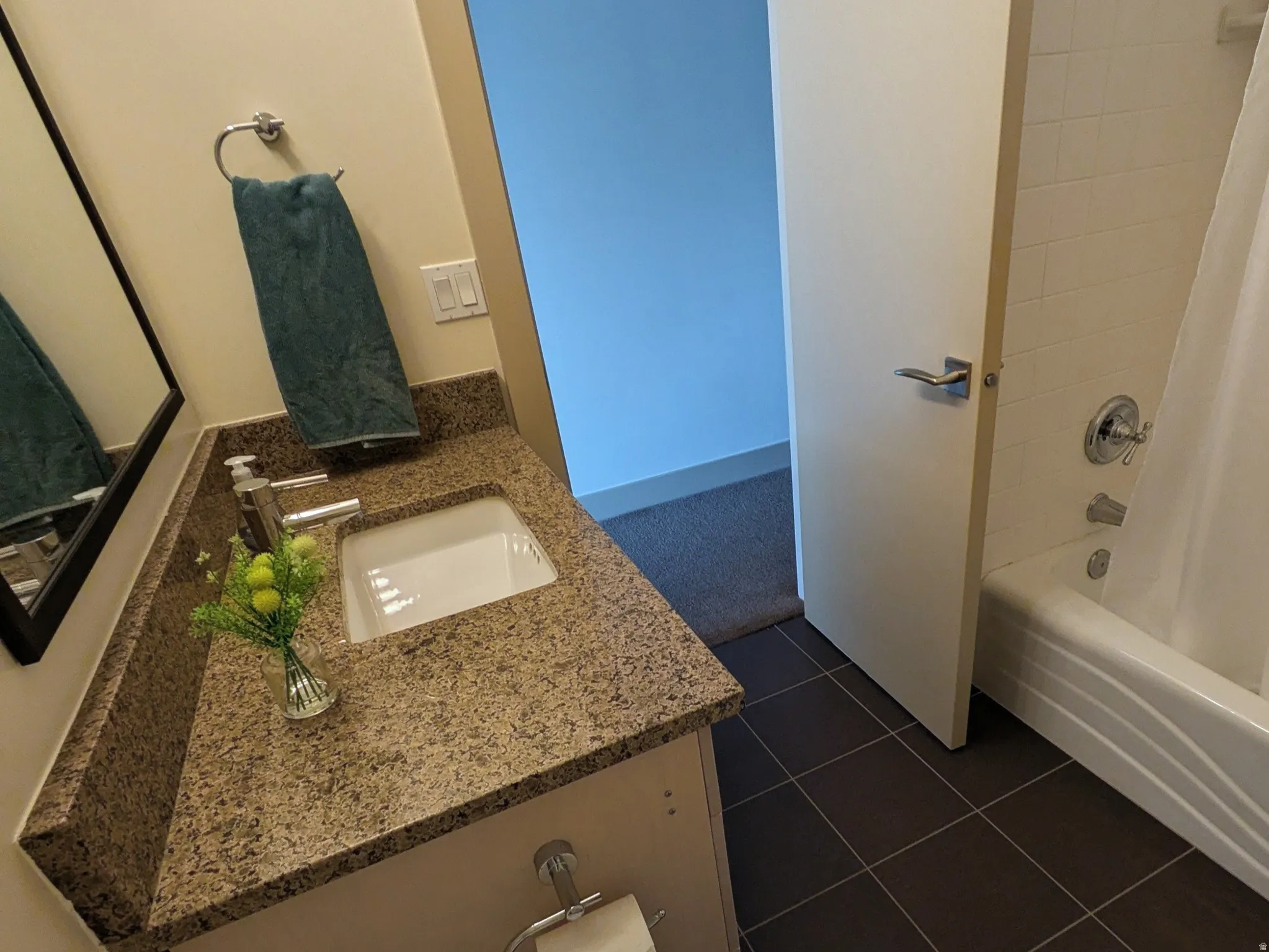 Bathroom featuring shower / bathtub combination with curtain, vanity, and dark tile patterned floors