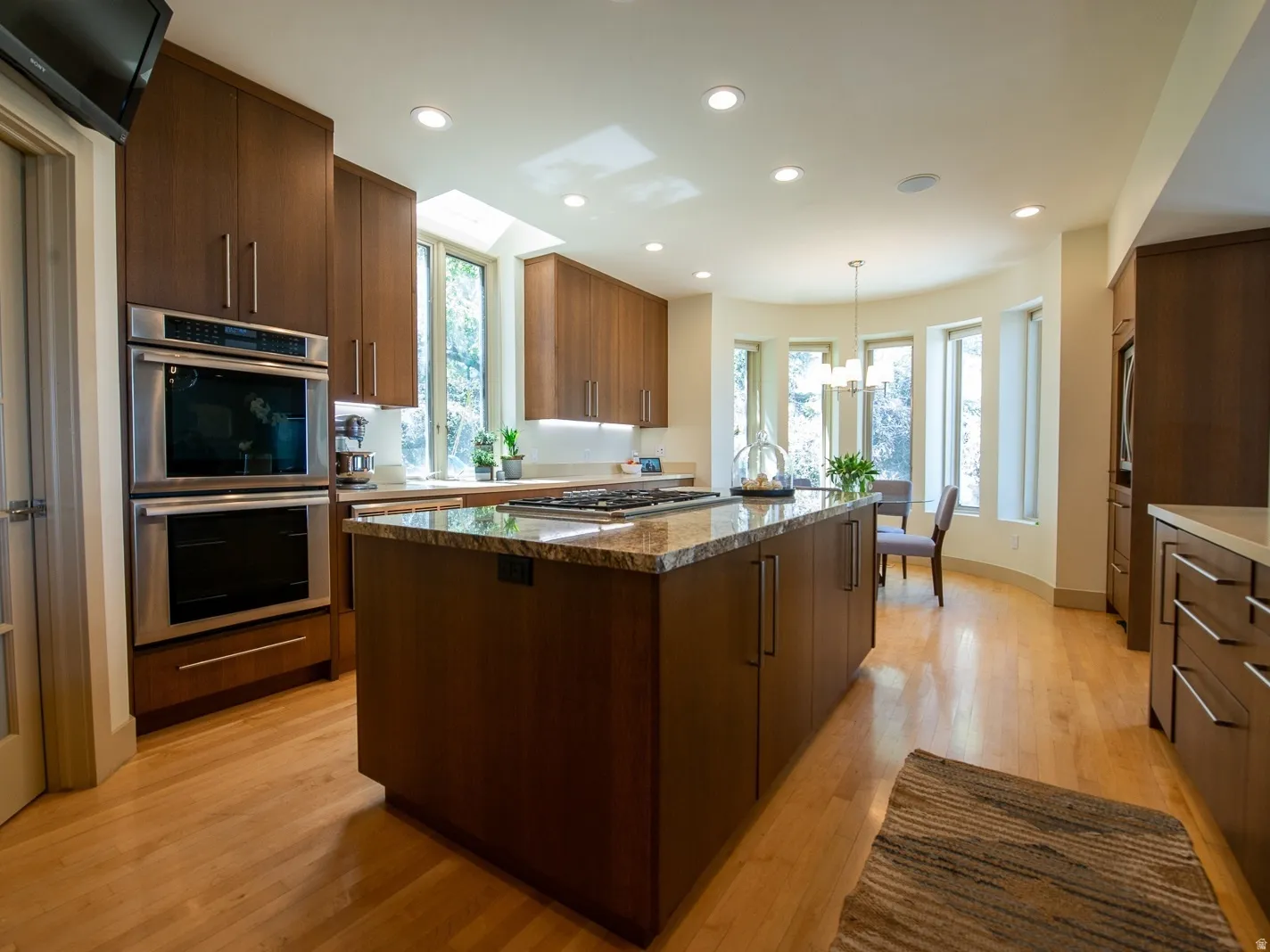 Kitchen with light hardwood  flooring, a center island, appliances with stainless steel finishes, granite countertops, pantry closet, double ovens and views of the mountains AND the Salt Lake valley!
