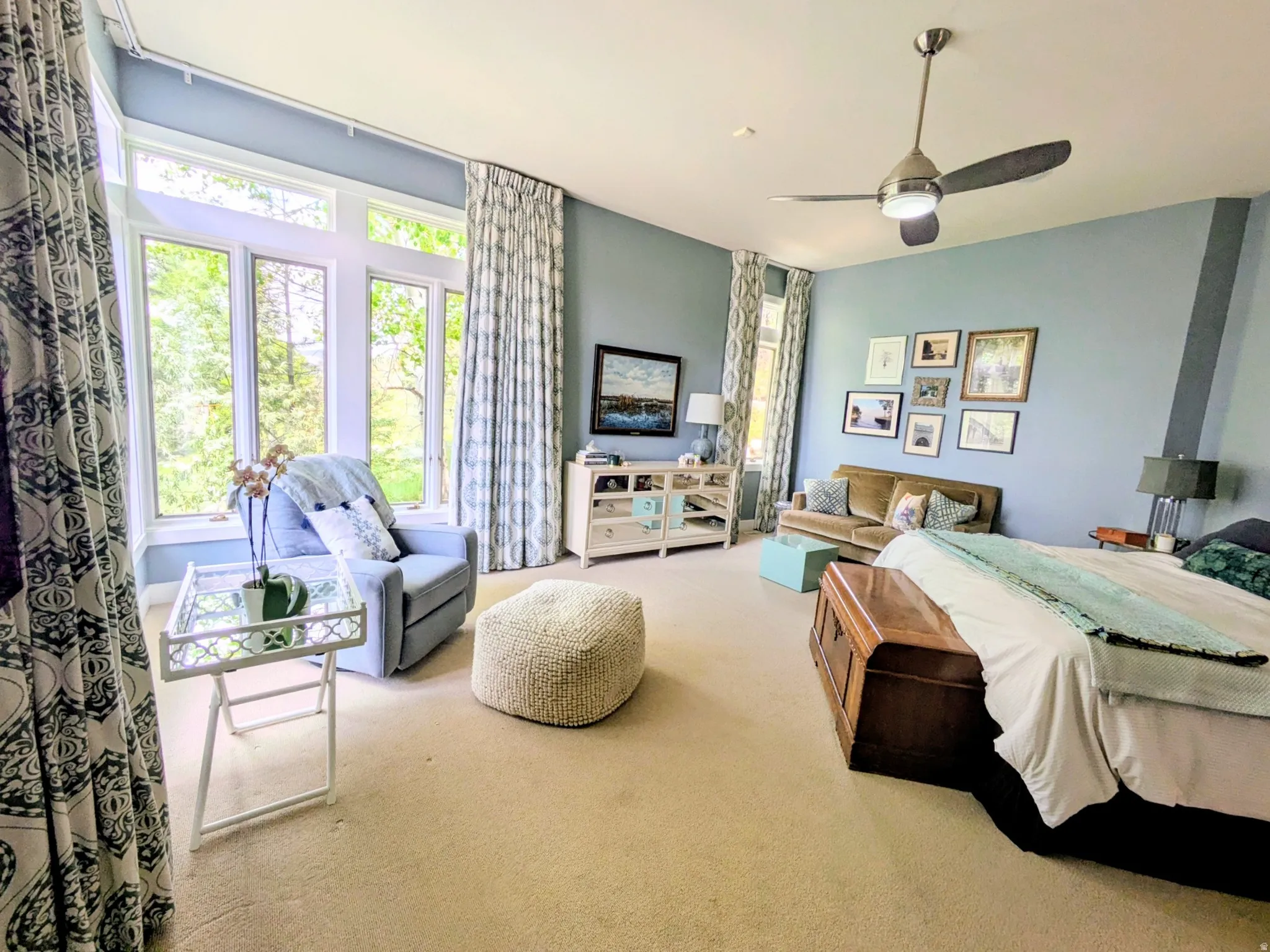 Spacious Master Bedroom featuring broad windows with architectural detailing, light carpeting, fireplace, a ceiling fan, auto draperies and beautiful valley view.