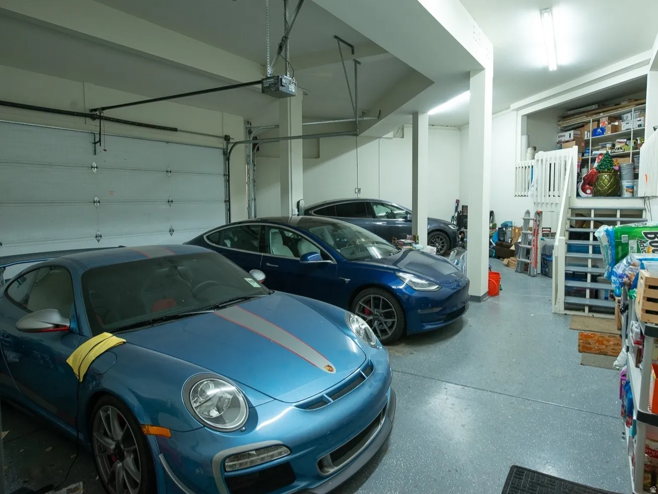 3 car Garage featuring a garage door opener, electric car charging station, and extra storage