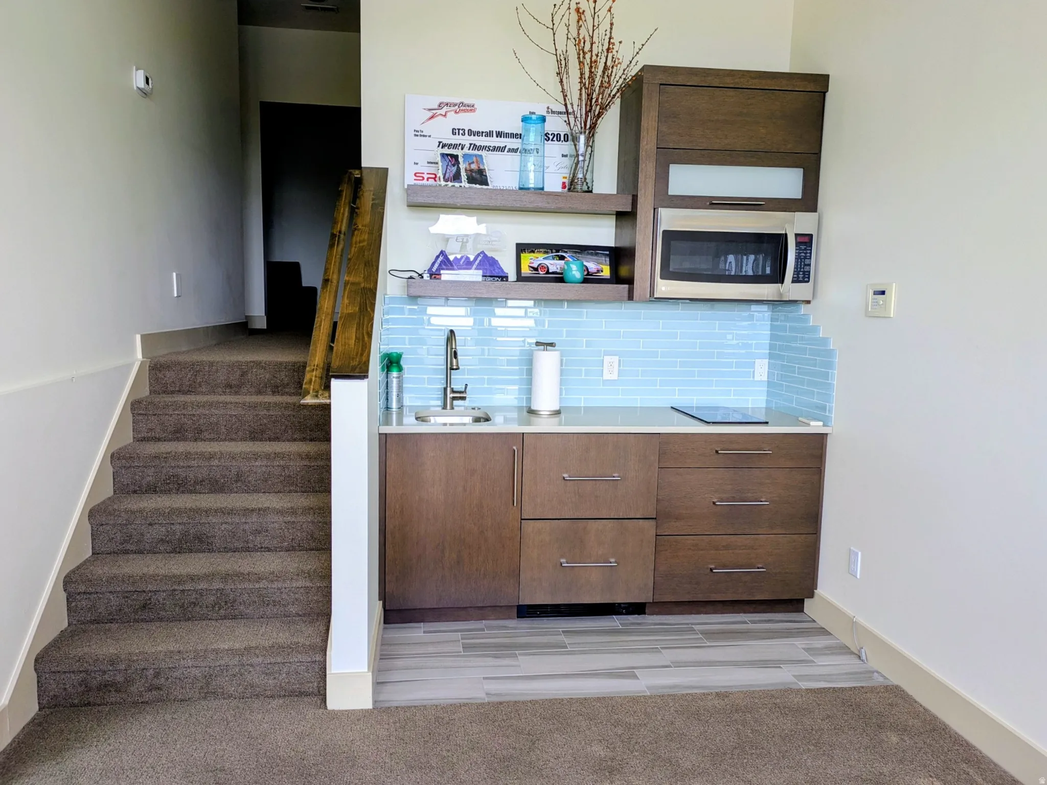 Compact kitchenette featuring wood-finish cabinetry, a light blue subway tile backsplash, and a built-in microwave
