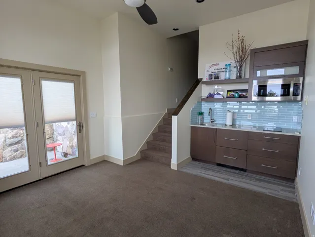 ADU living room-kitchenette with dark carpet and a ceiling fan