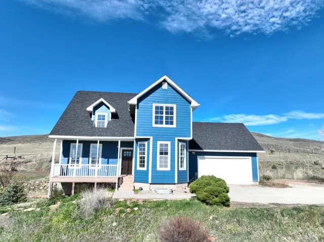 Traditional home with roof with shingles, covered porch, an attached garage, and driveway