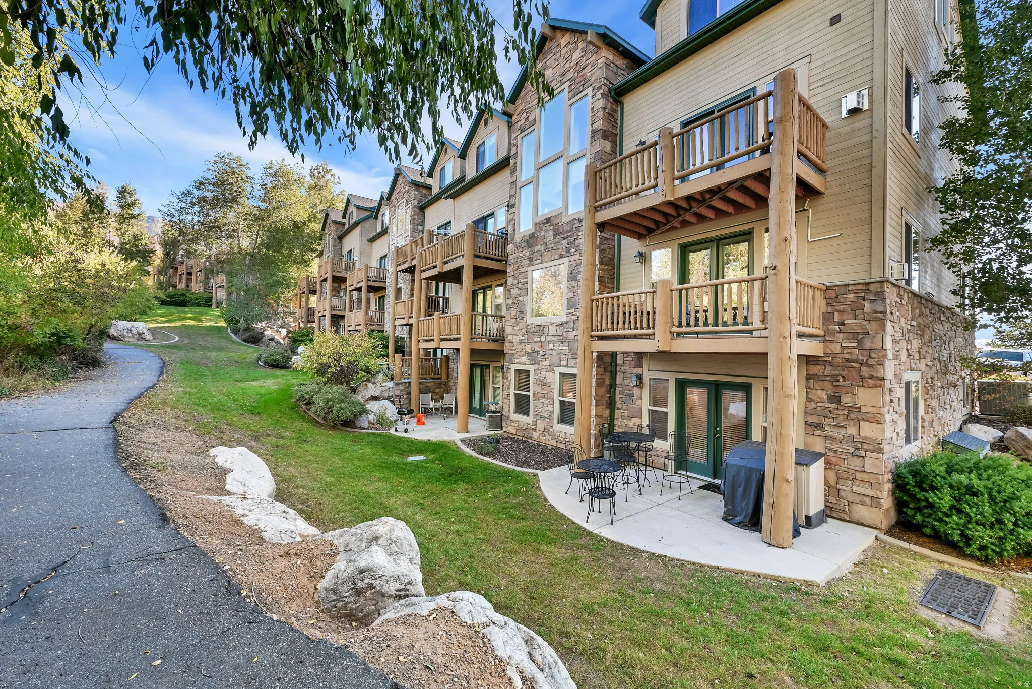 Back of house with stone siding, a yard, a patio area, a balcony, and french doors
