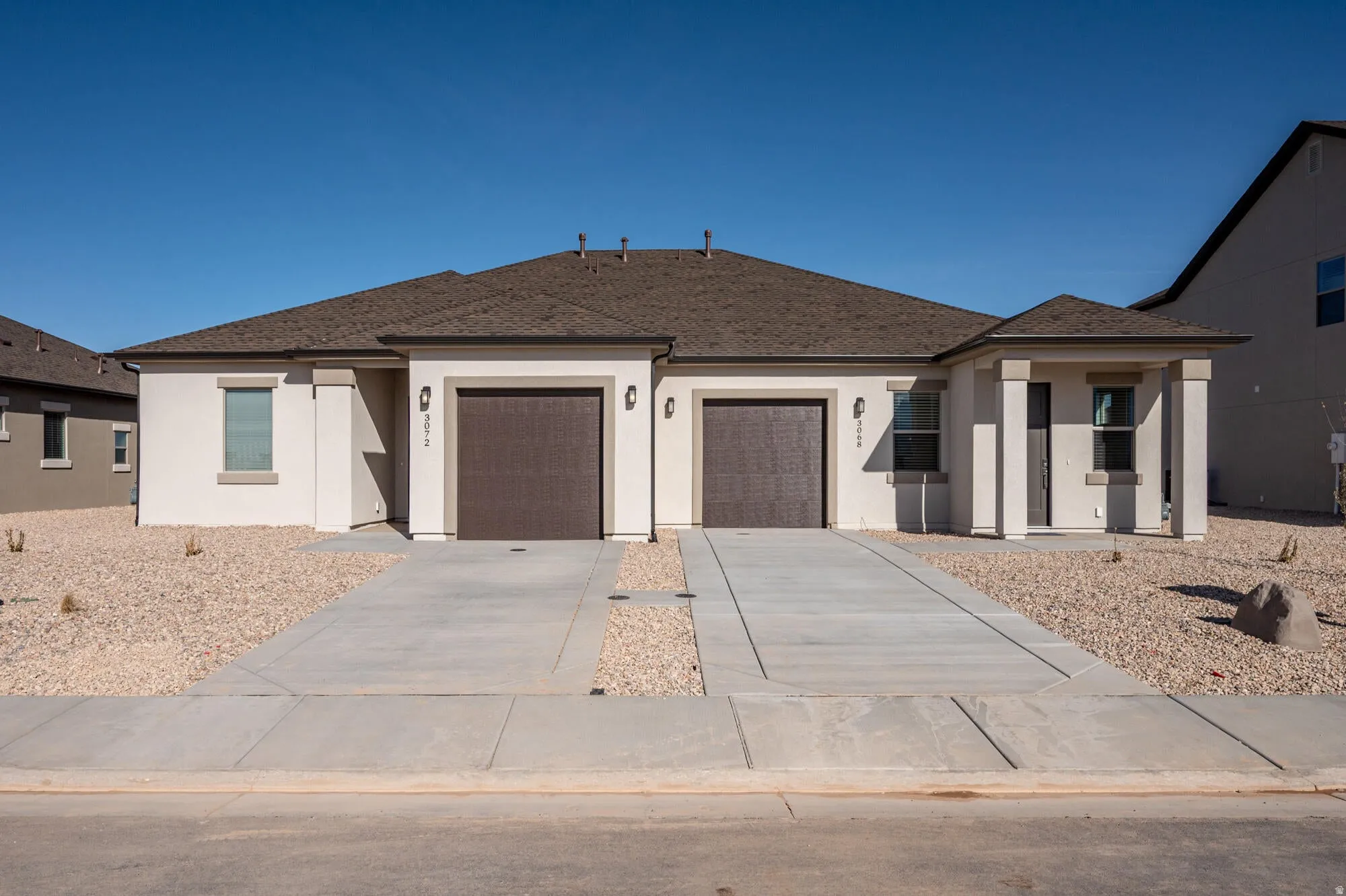 View of front of property with a garage, concrete driveway, stucco siding, and roof with shingles
