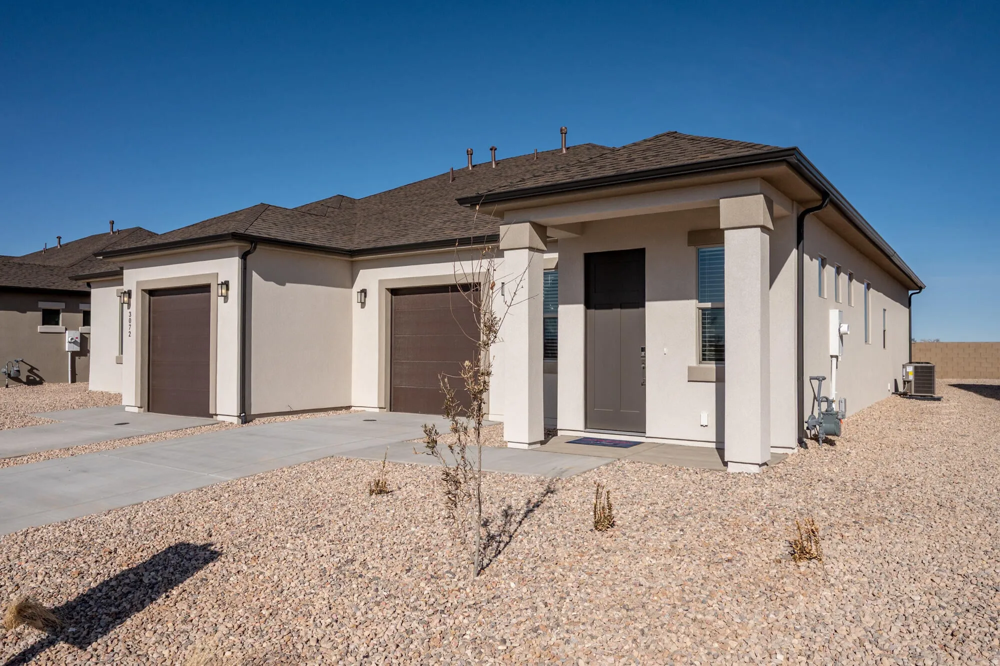 View of front facade featuring a garage, stucco siding, driveway, and roof with shingles