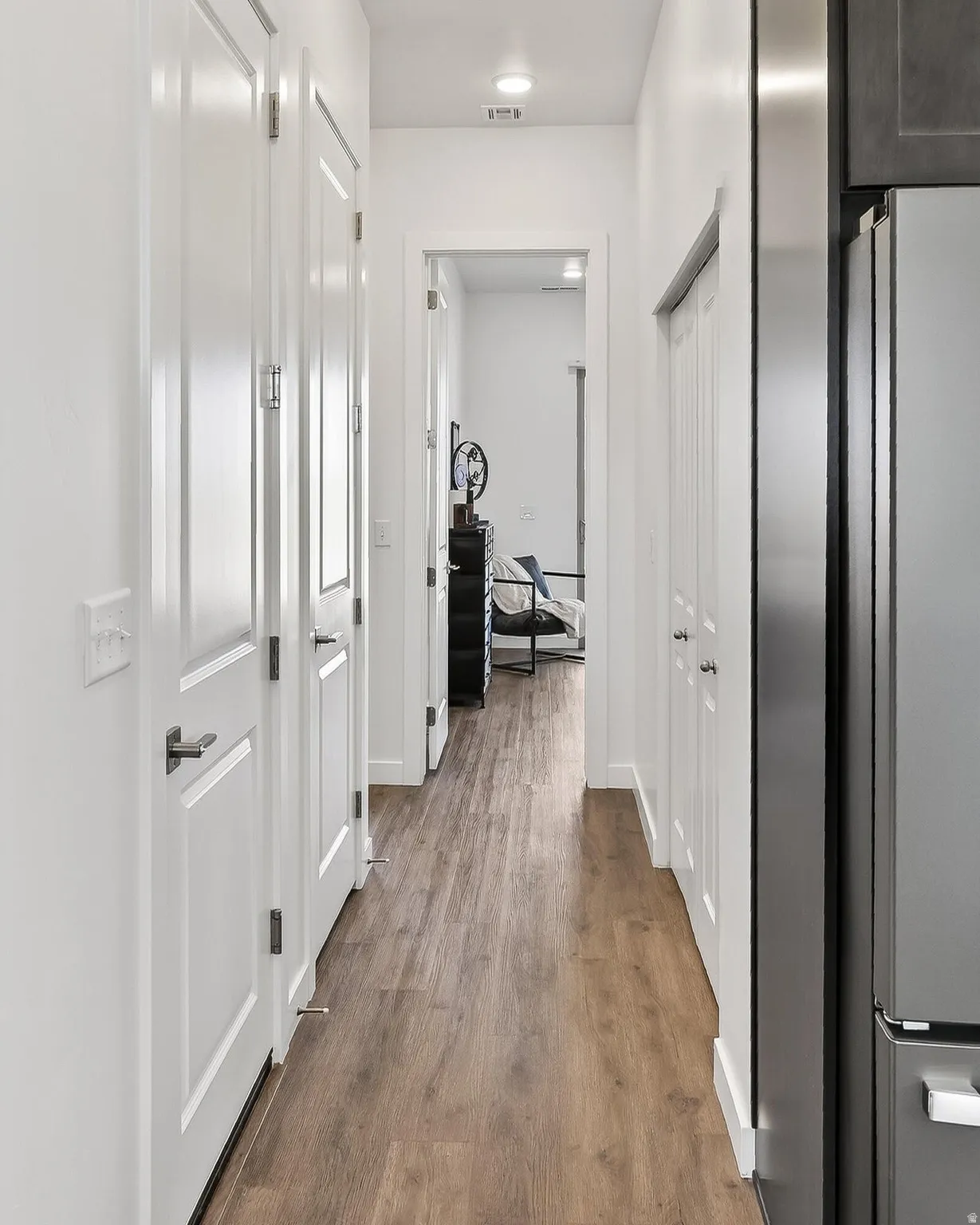 Hallway with dark wood-type flooring and baseboards