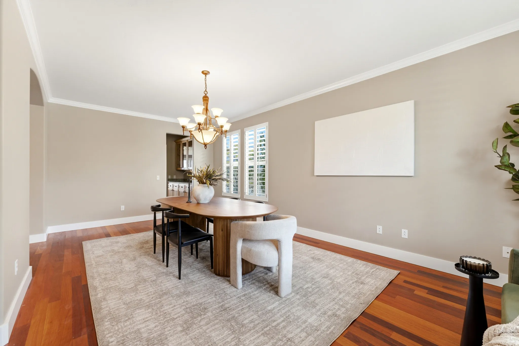 Dining room with wood finished floors, suspended lighting, crown molding, and arched walkways