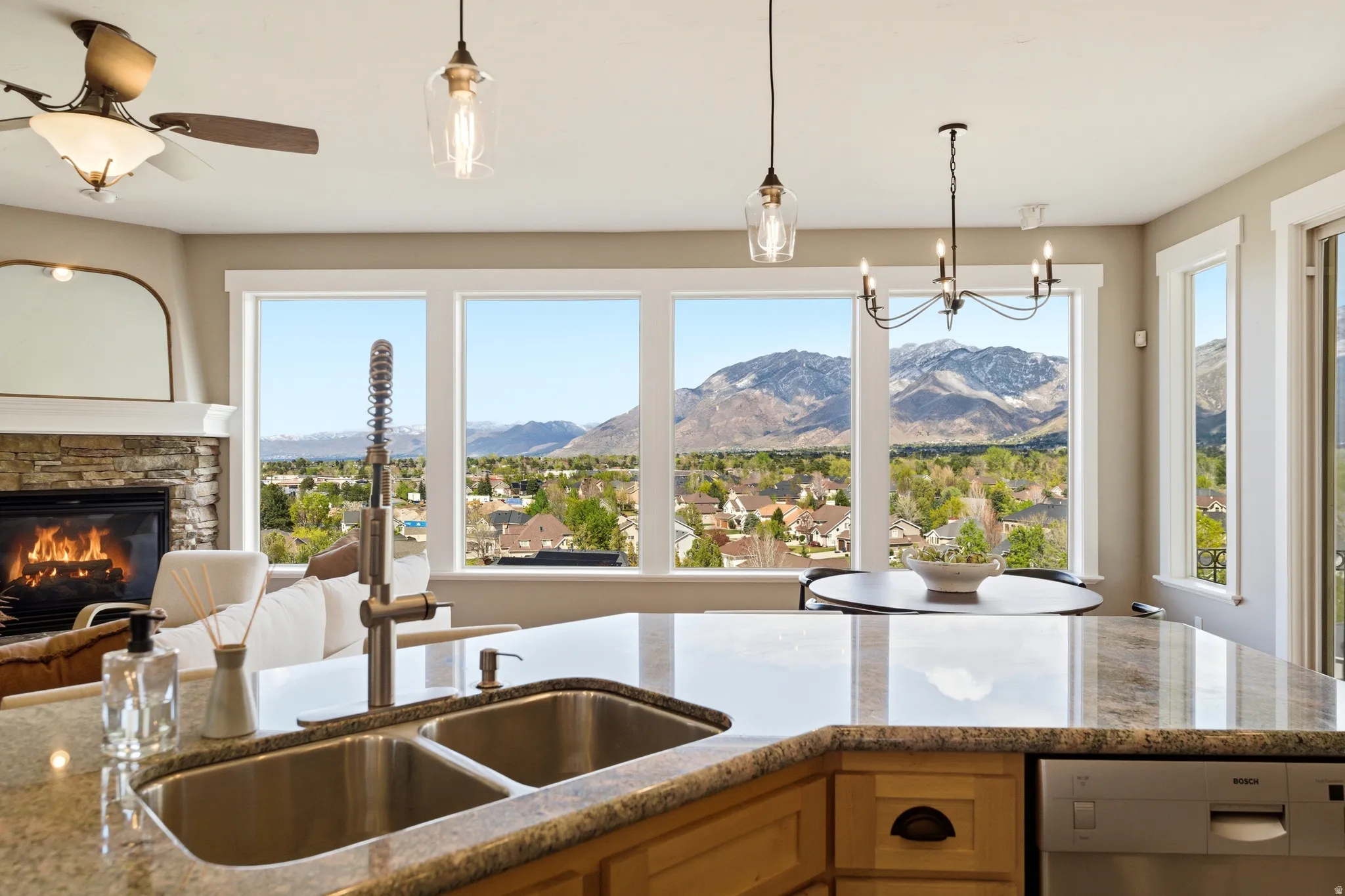 Kitchen featuring light stone counters, stainless steel dishwasher, open floor plan, and a stone fireplace