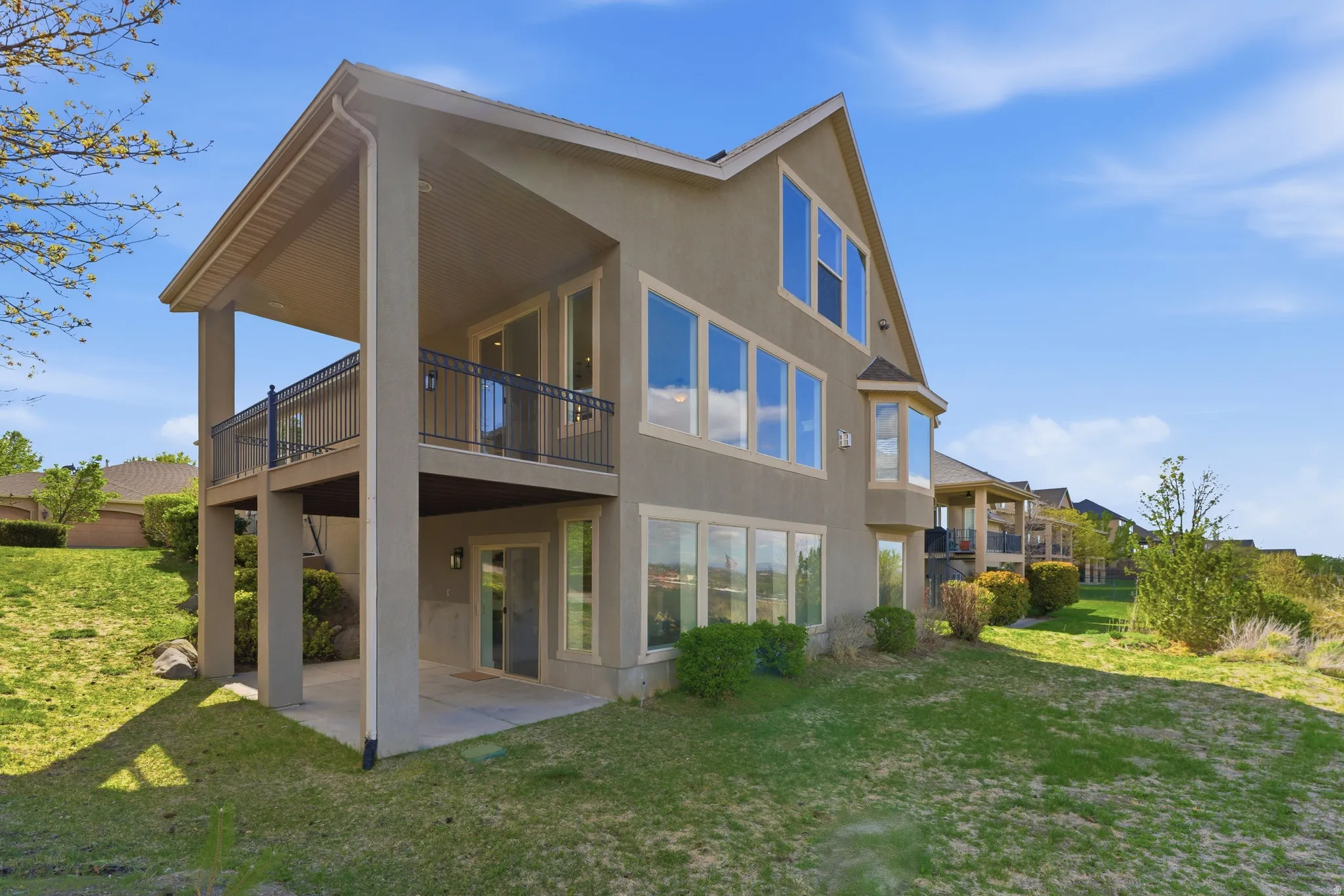 Rear view of property with a patio, stucco siding, a yard, and a balcony