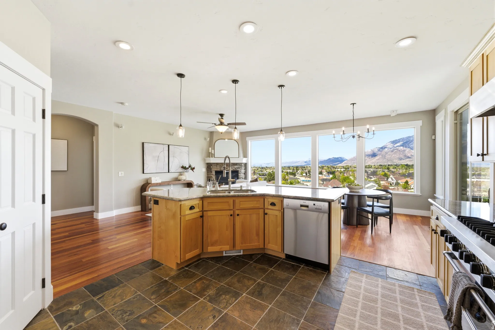Kitchen with light stone counters, an island with sink, stone tile floors, a mountain view, and stainless steel appliances
