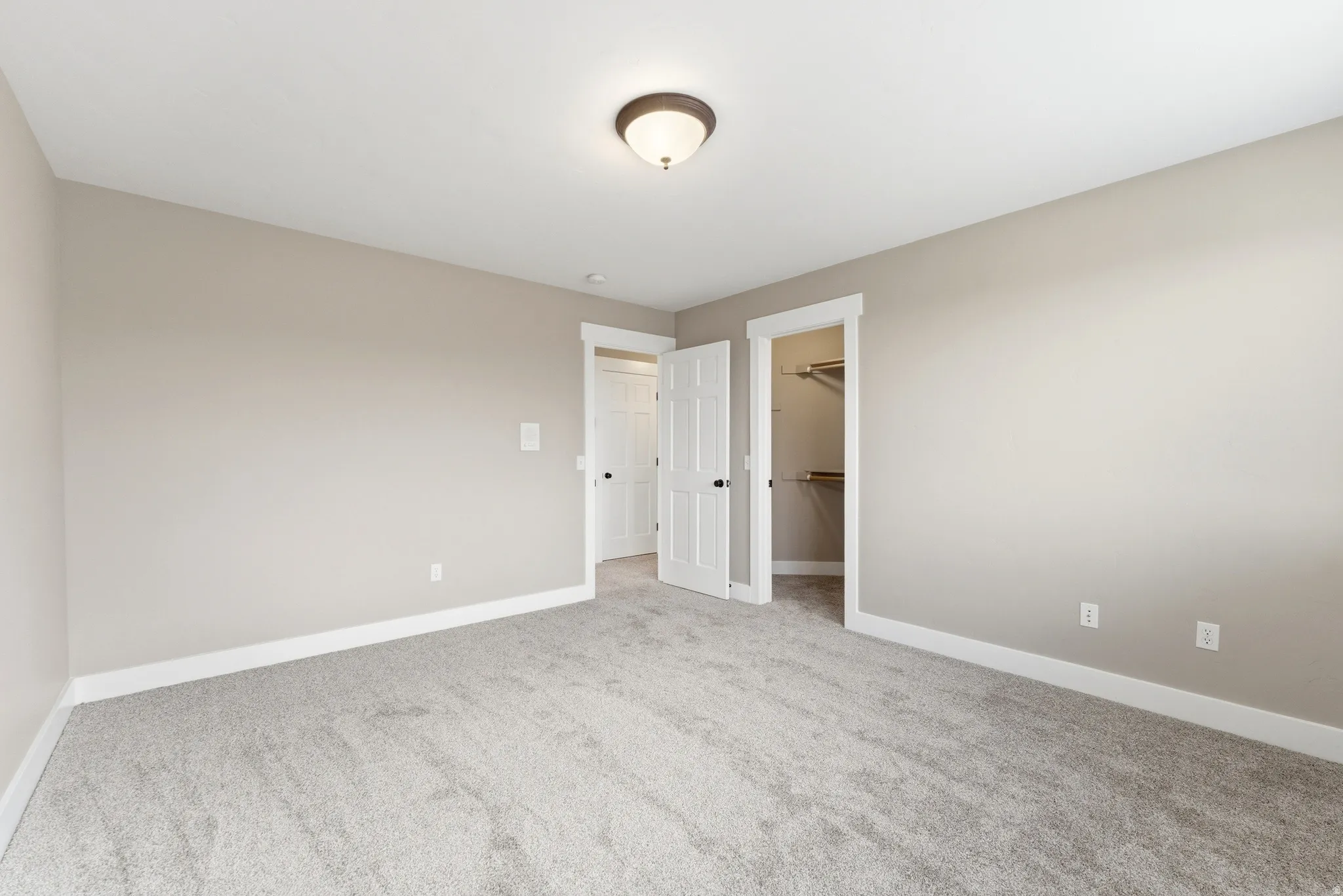 Unfurnished bedroom with light colored carpet and a spacious closet