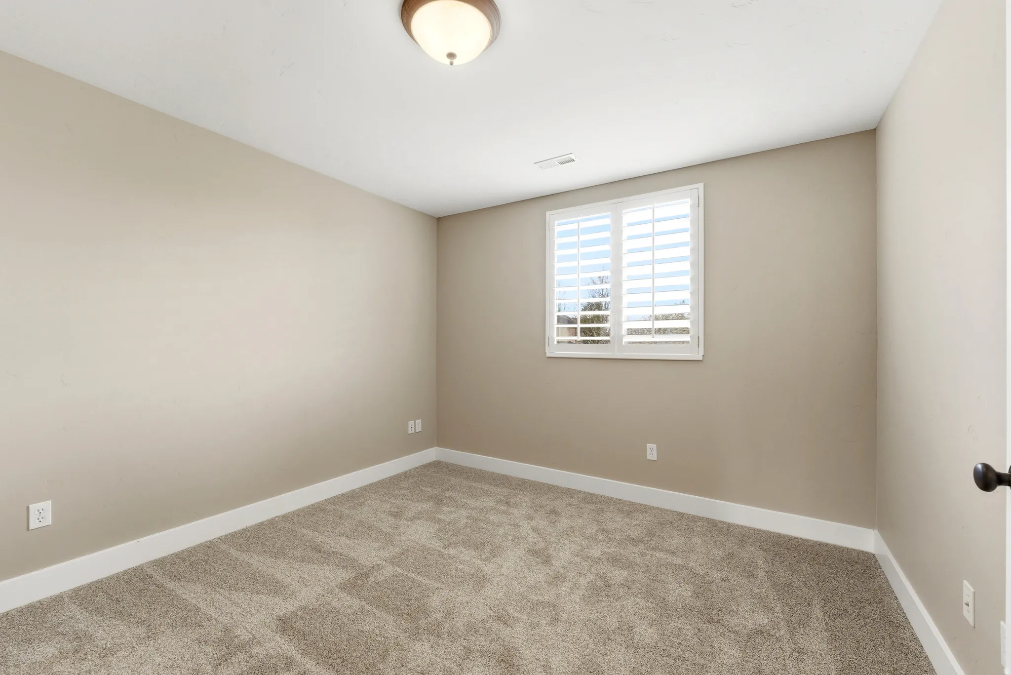 Empty room with light colored carpet and baseboards