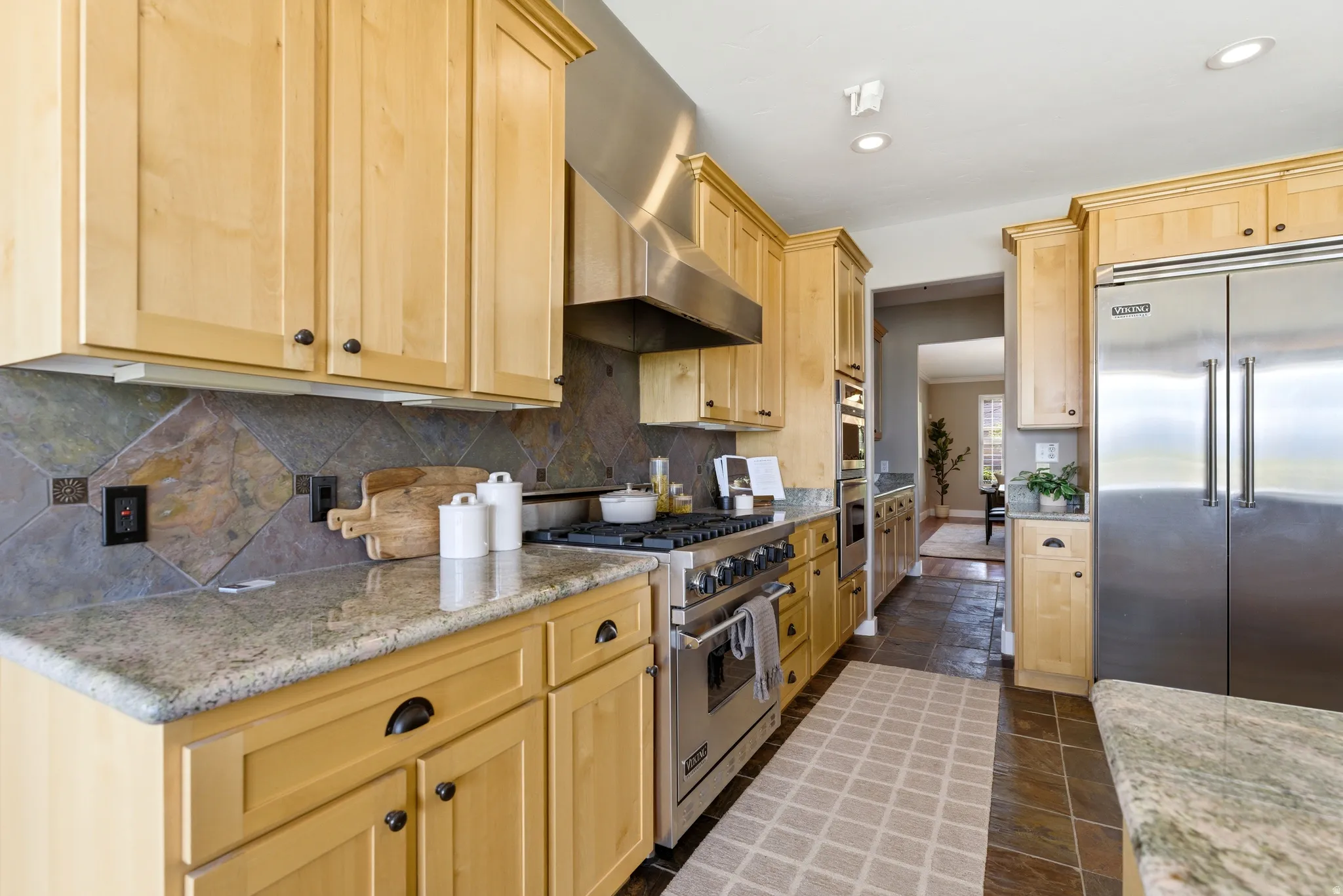 Kitchen featuring light wood finish cabinets, high end Viking appliances, light stone counters, recessed lighting, and dark stone finish floors
