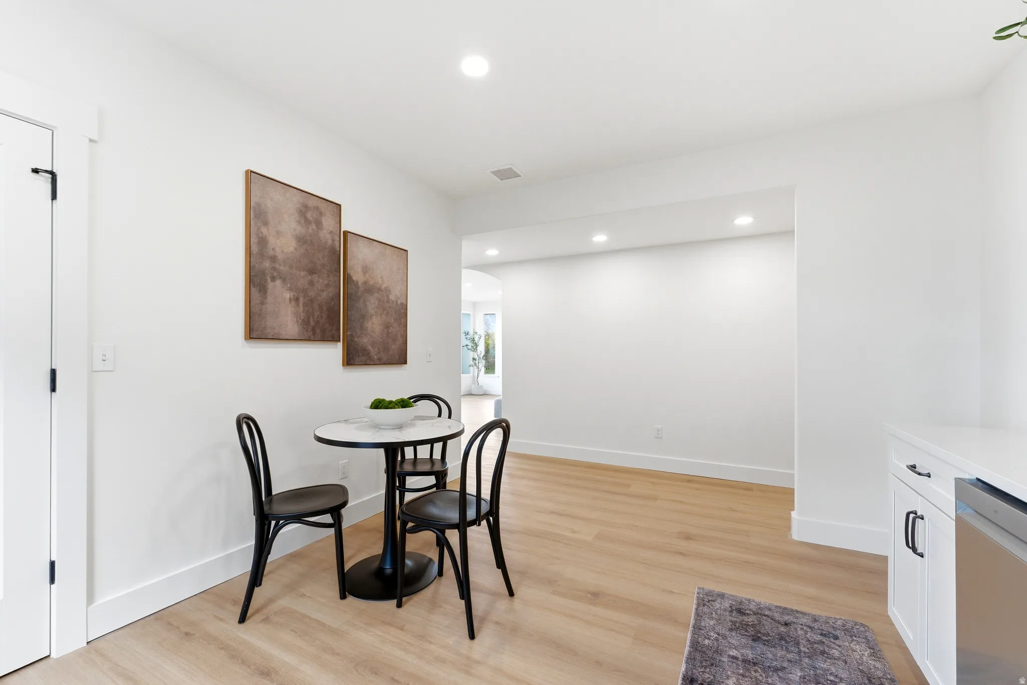 Dining area with arched walkways, light wood finished floors, and recessed lighting