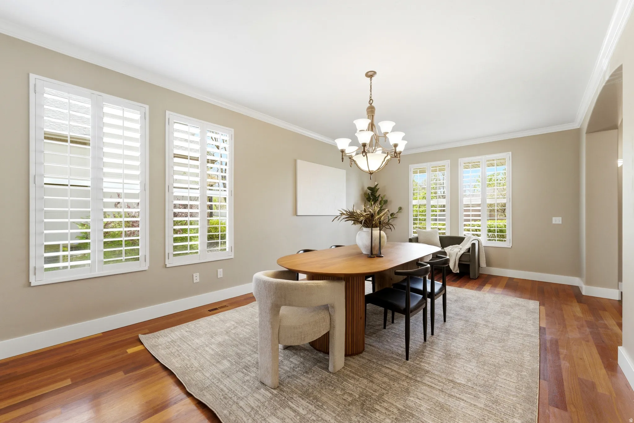 Dining area with a chandelier, wood finished floors, and ornamental molding