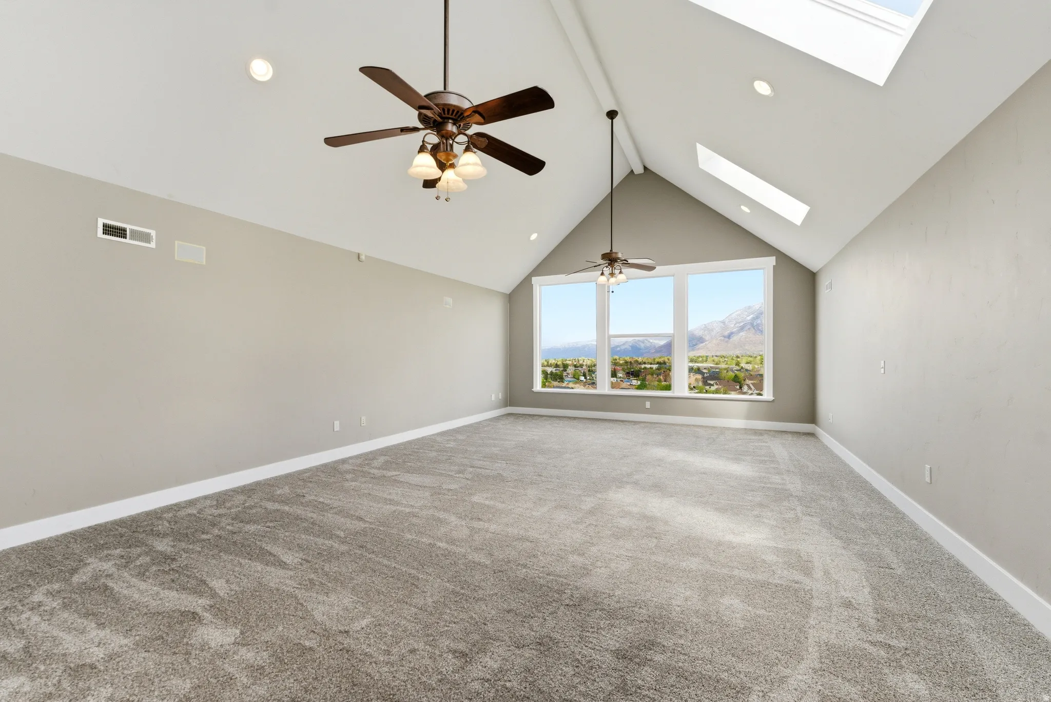 Unfurnished living room with a mountain view, ceiling fan, carpet flooring, a skylight, and recessed lighting