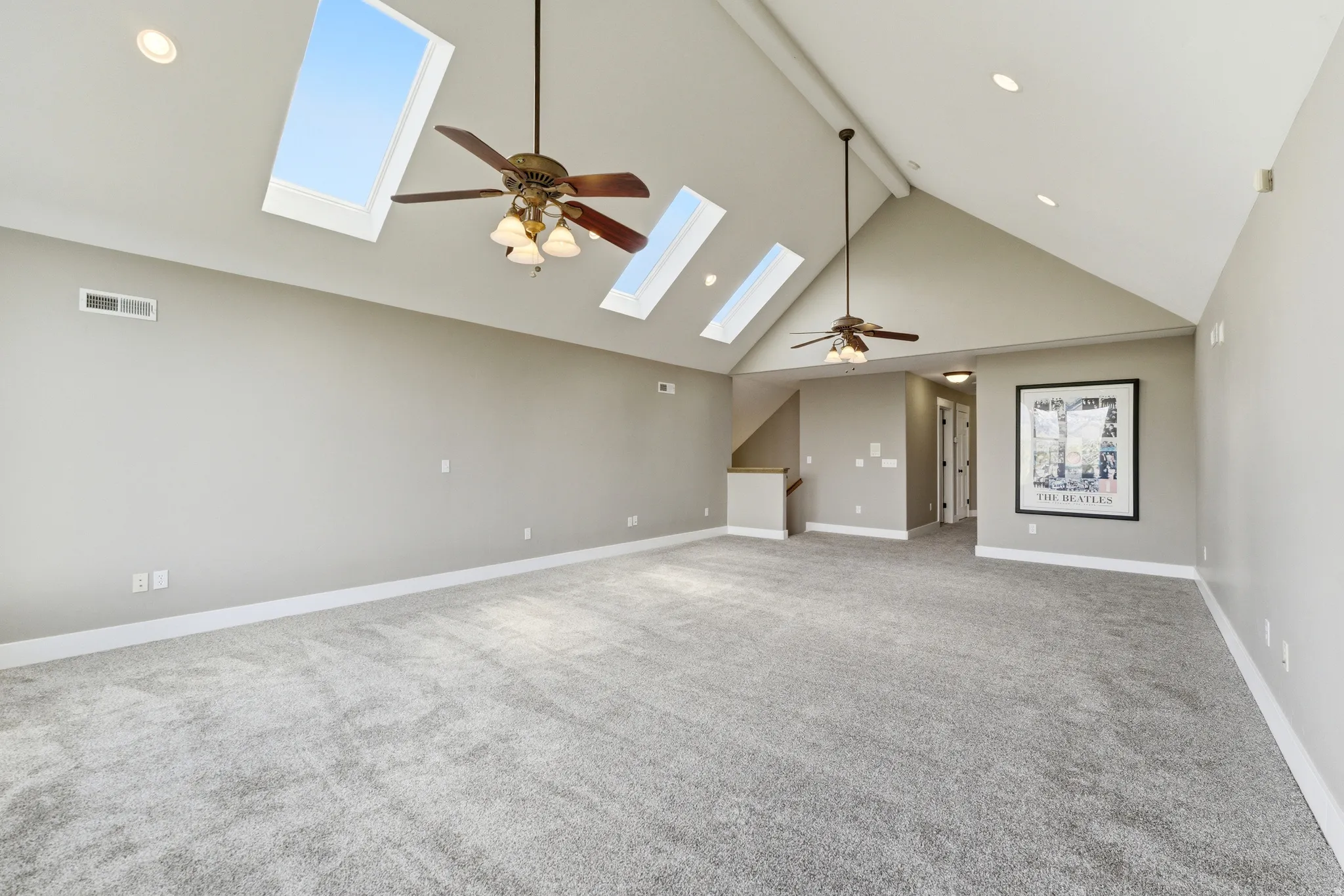Unfurnished living room featuring ceiling fan, light colored carpet, a skylight, and recessed lighting