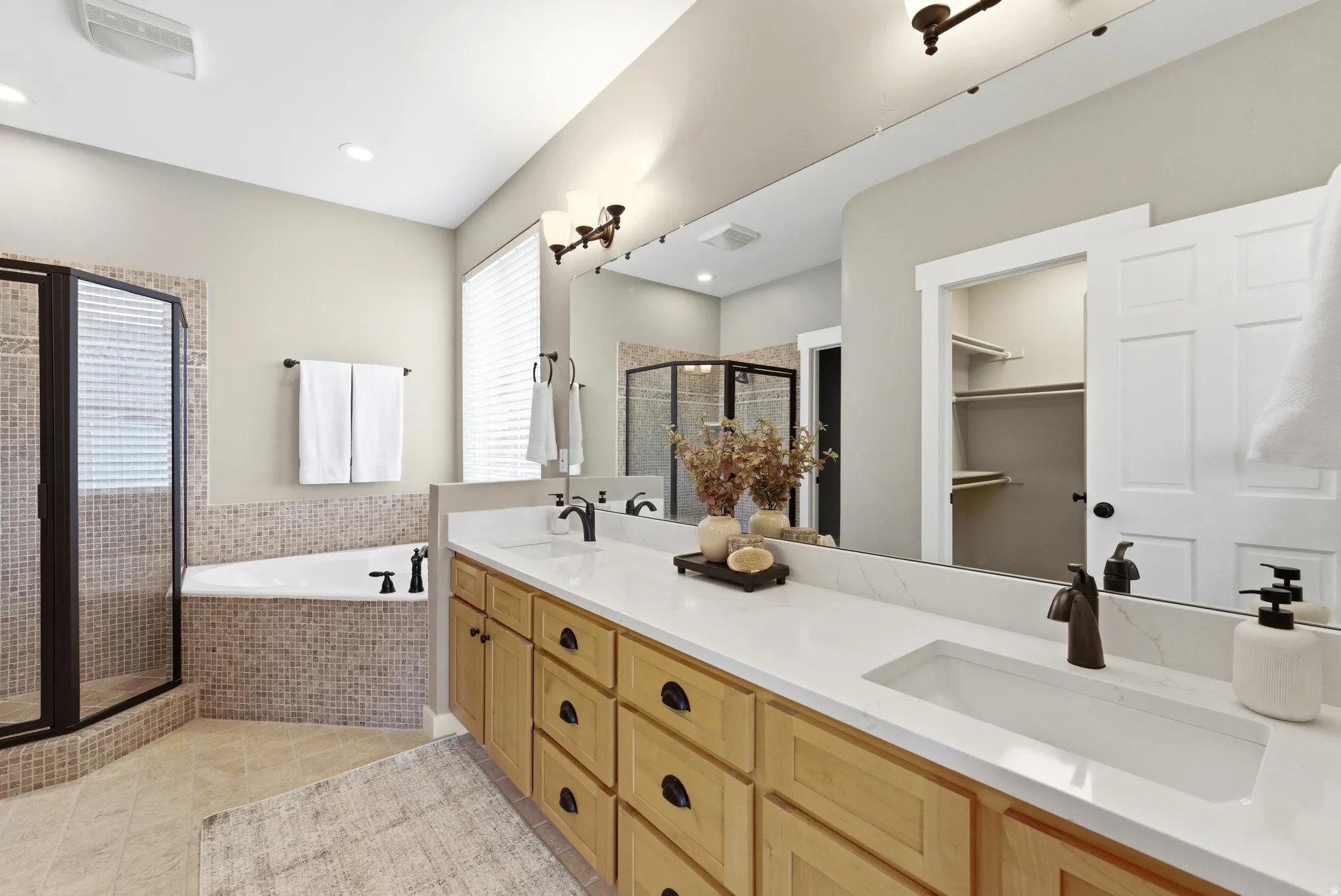 Master bath featuring a shower, double vanity, large soaking tub, new quartz countertops and faucets, and a walk in closet. New toilets in all 4 bathrooms.