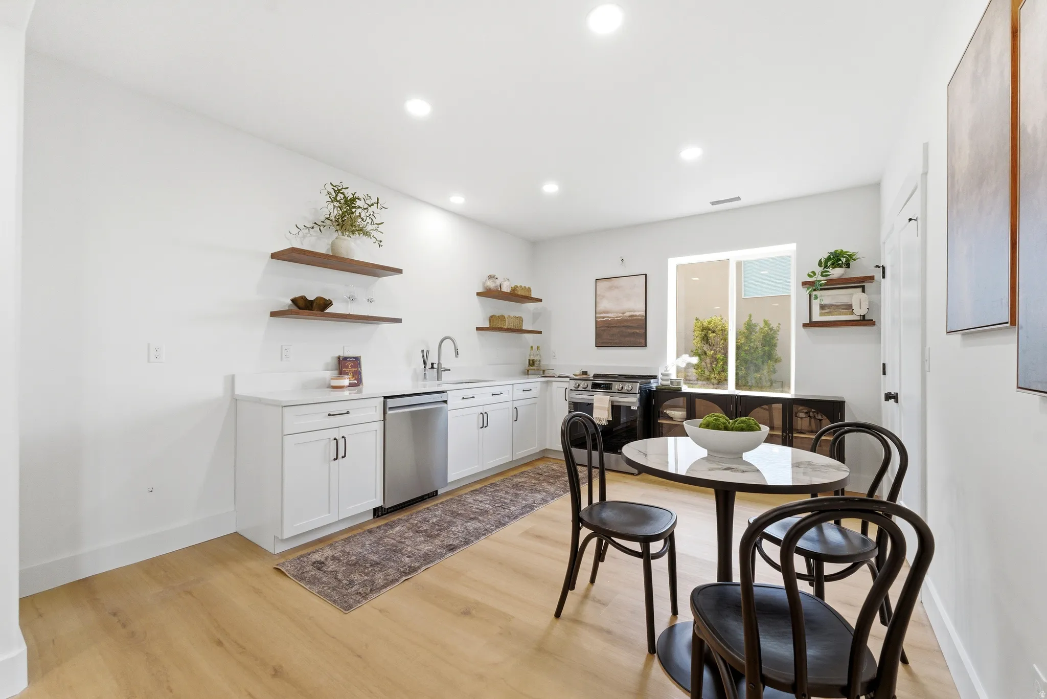 Kitchen with open shelves, stainless steel appliances, white cabinetry, light wood-style flooring, and recessed lighting