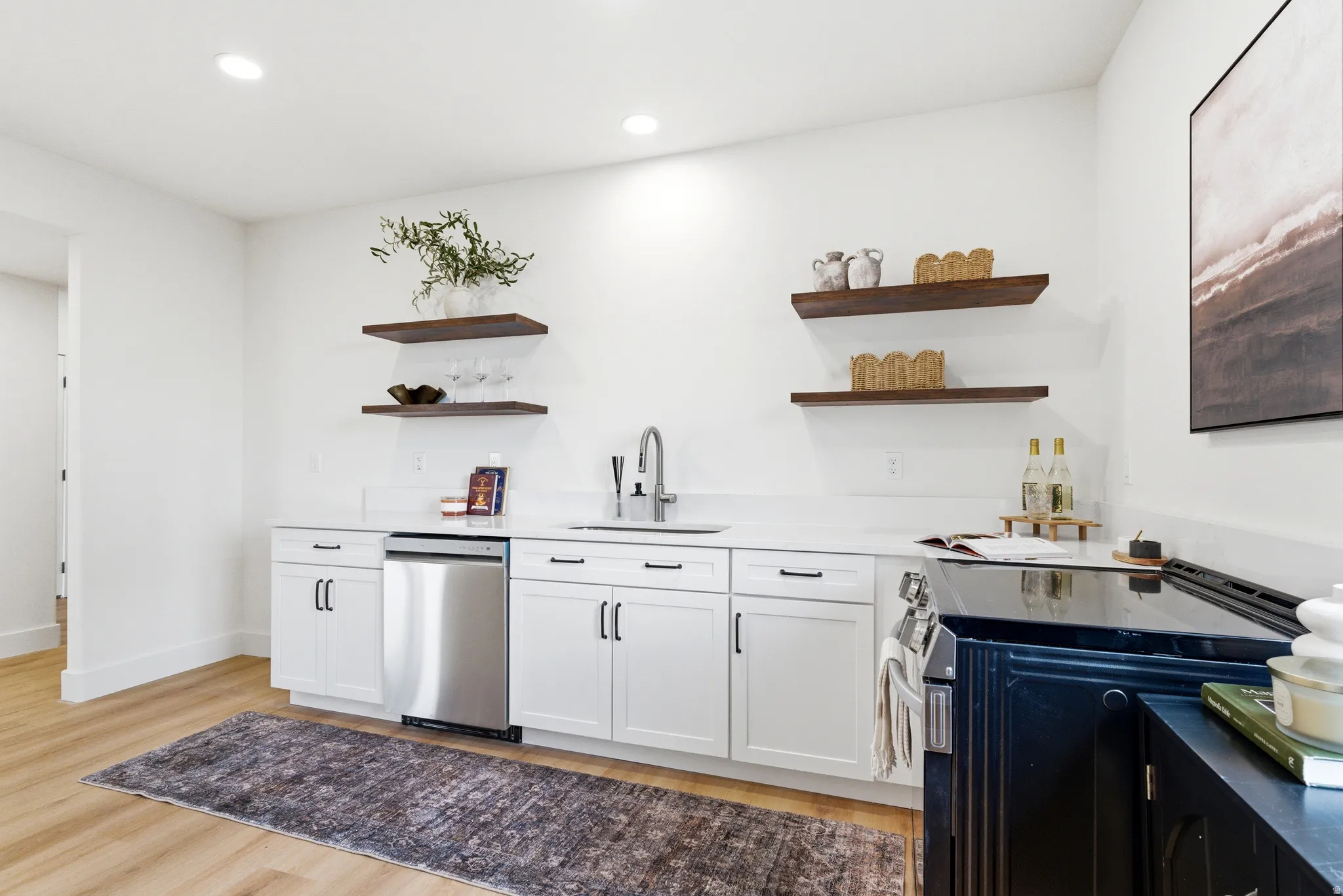 Kitchen with stainless steel appliances, new white cabinets, open shelves, light wood-style floors, and new quartz  countertops