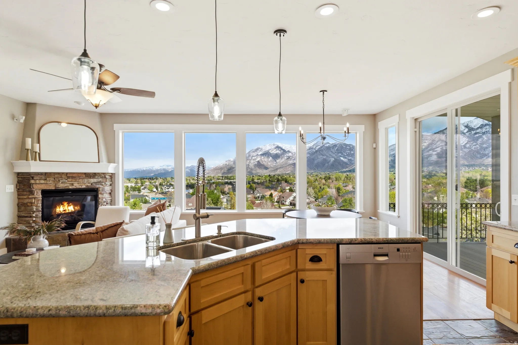 Kitchen featuring stainless steel dishwasher, a fireplace, light stone countertops, hanging light fixtures, and open floor plan