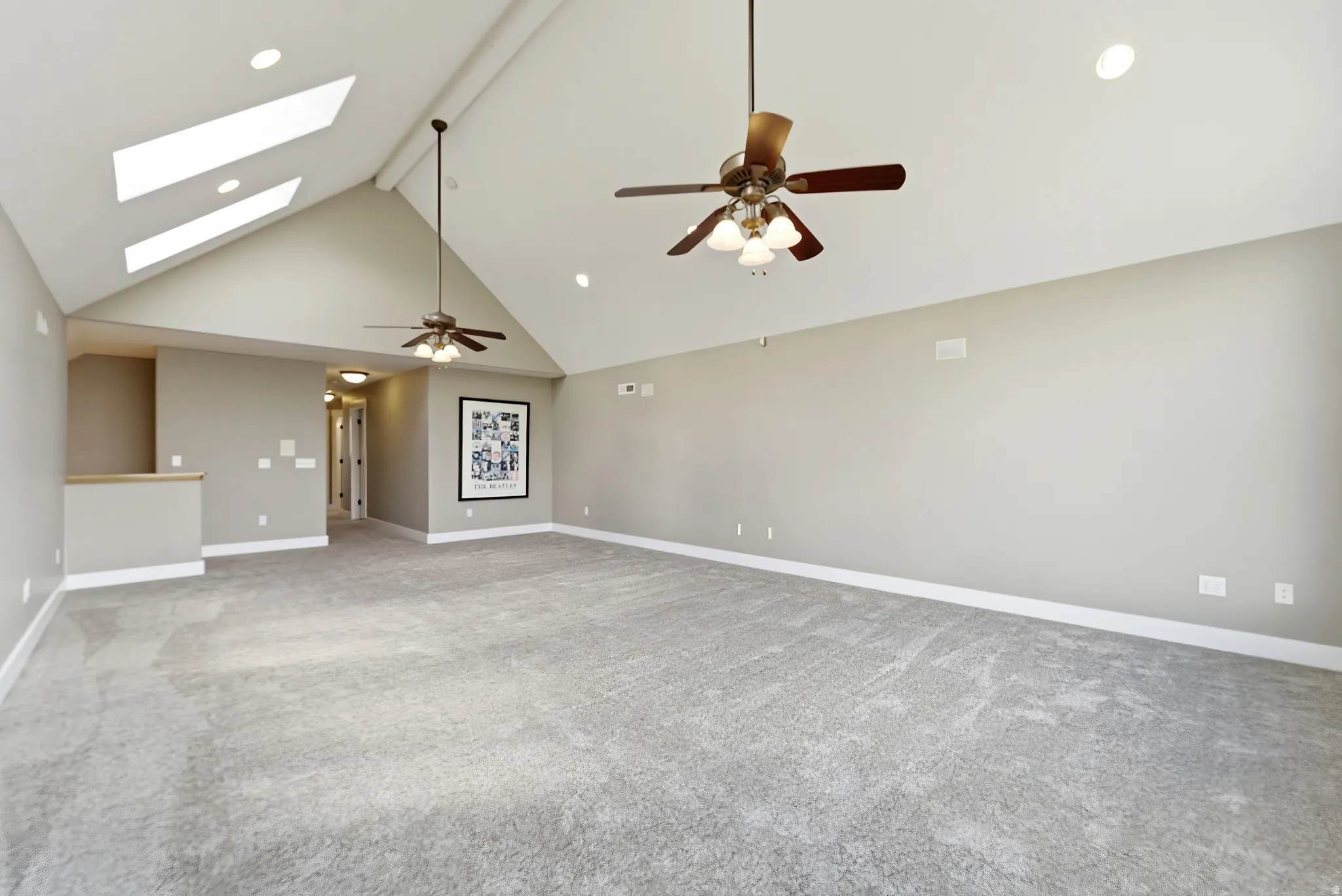 Empty room featuring ceiling fan, a skylight, light carpet, and recessed lighting