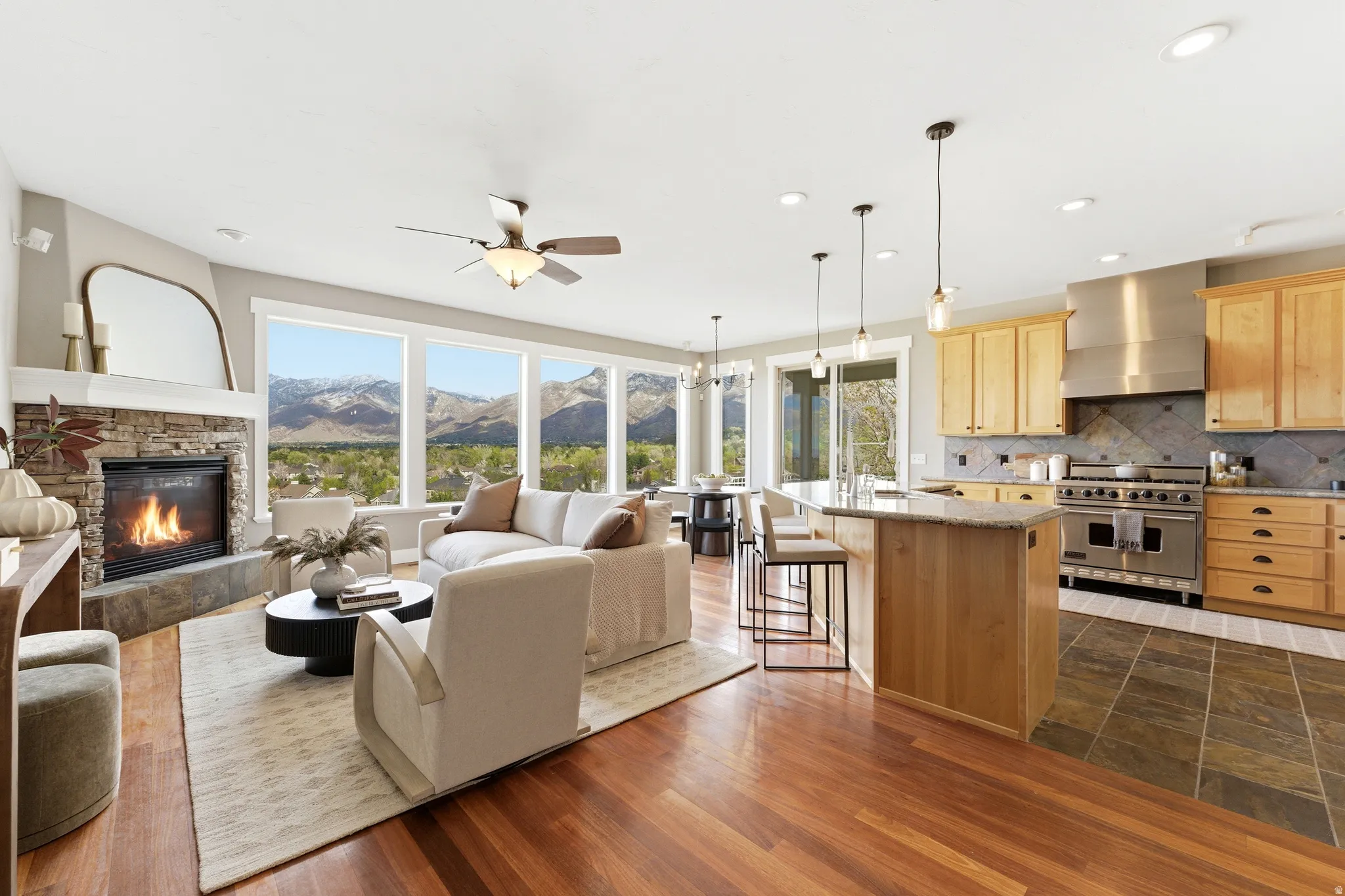 Living room  on main level, featuring a mountain view, a fireplace, a ceiling fan, hanging lights, and dark wood-style flooring