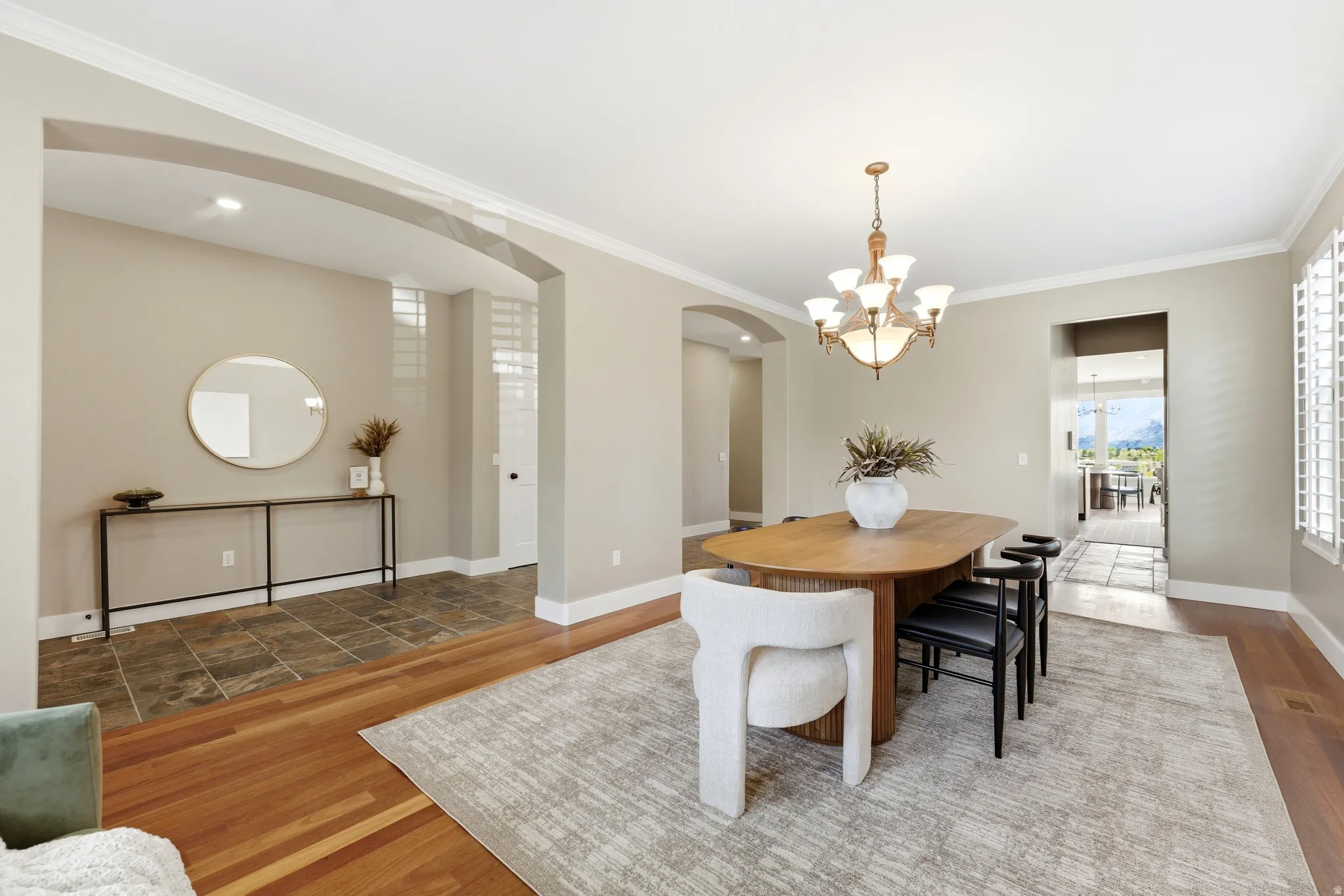 Dining area with arched walkways, wood finished floors, crown molding, and hanging lights
