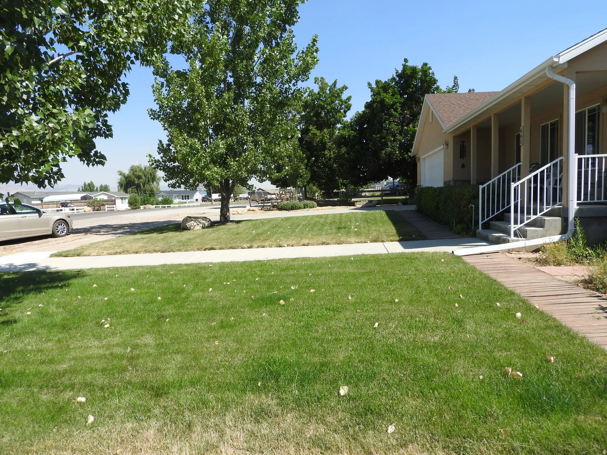 View of green lawn with a porch, an attached garage, and a residential view