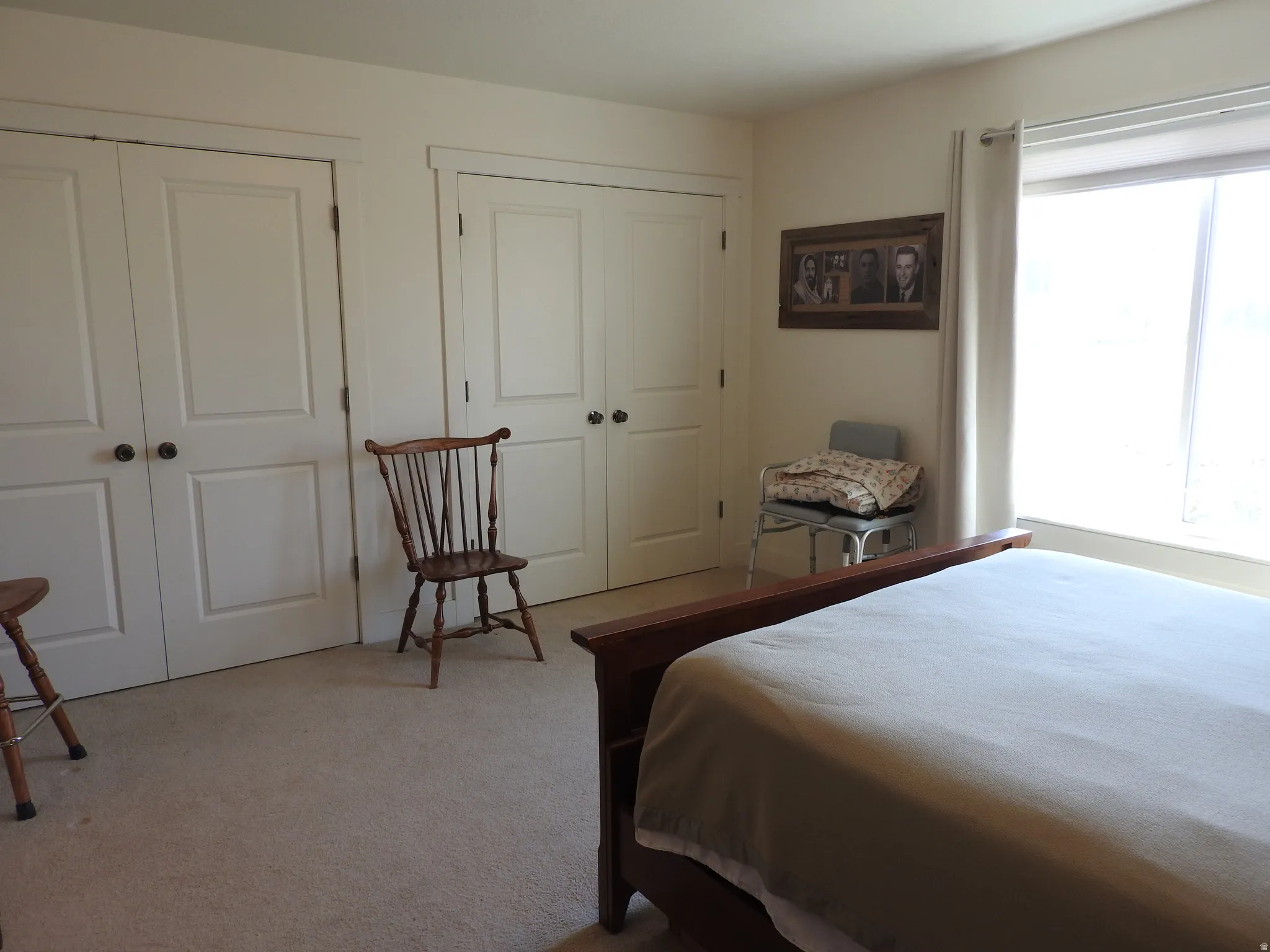 Bedroom with light colored carpet and multiple closets