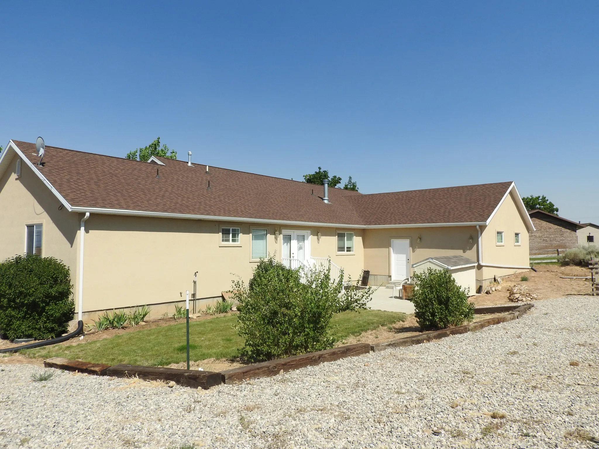 Back of property featuring stucco siding, a shingled roof, and a yard
