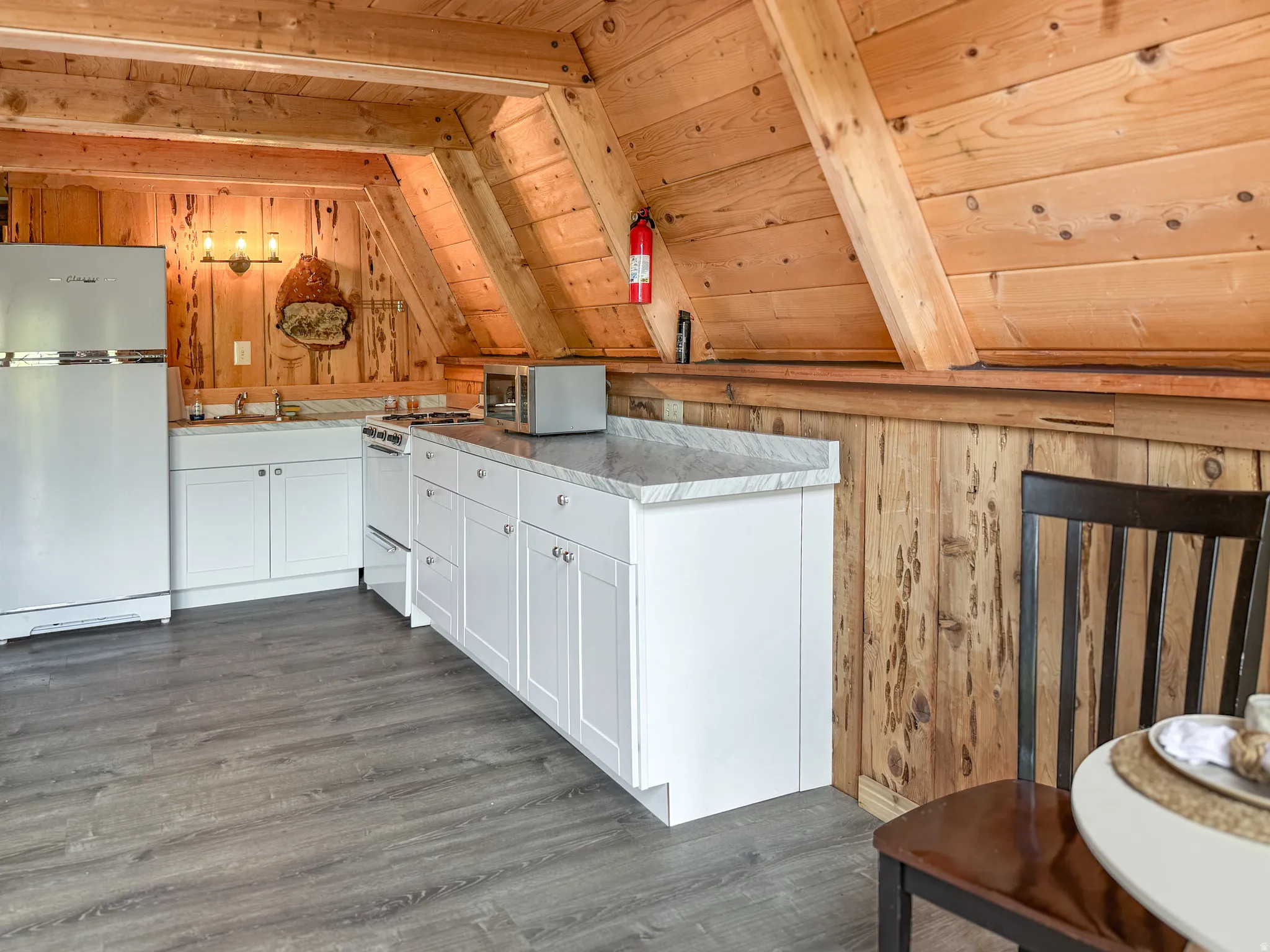 Kitchen featuring freestanding refrigerator, wood walls, white cabinetry, a vaulted wooden ceiling, and gas range gas stove