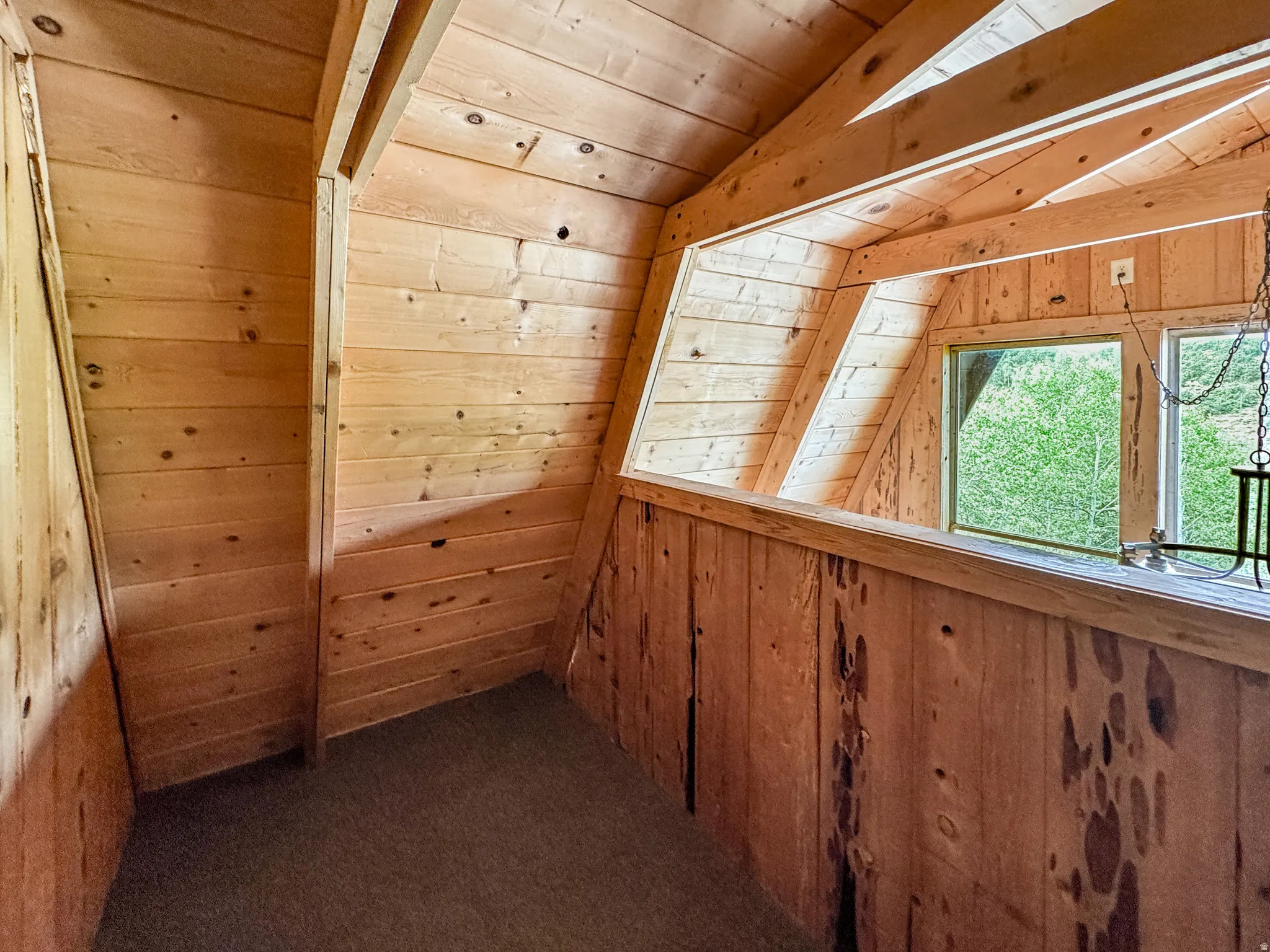 Empty room with wood walls and a vaulted wooden ceiling