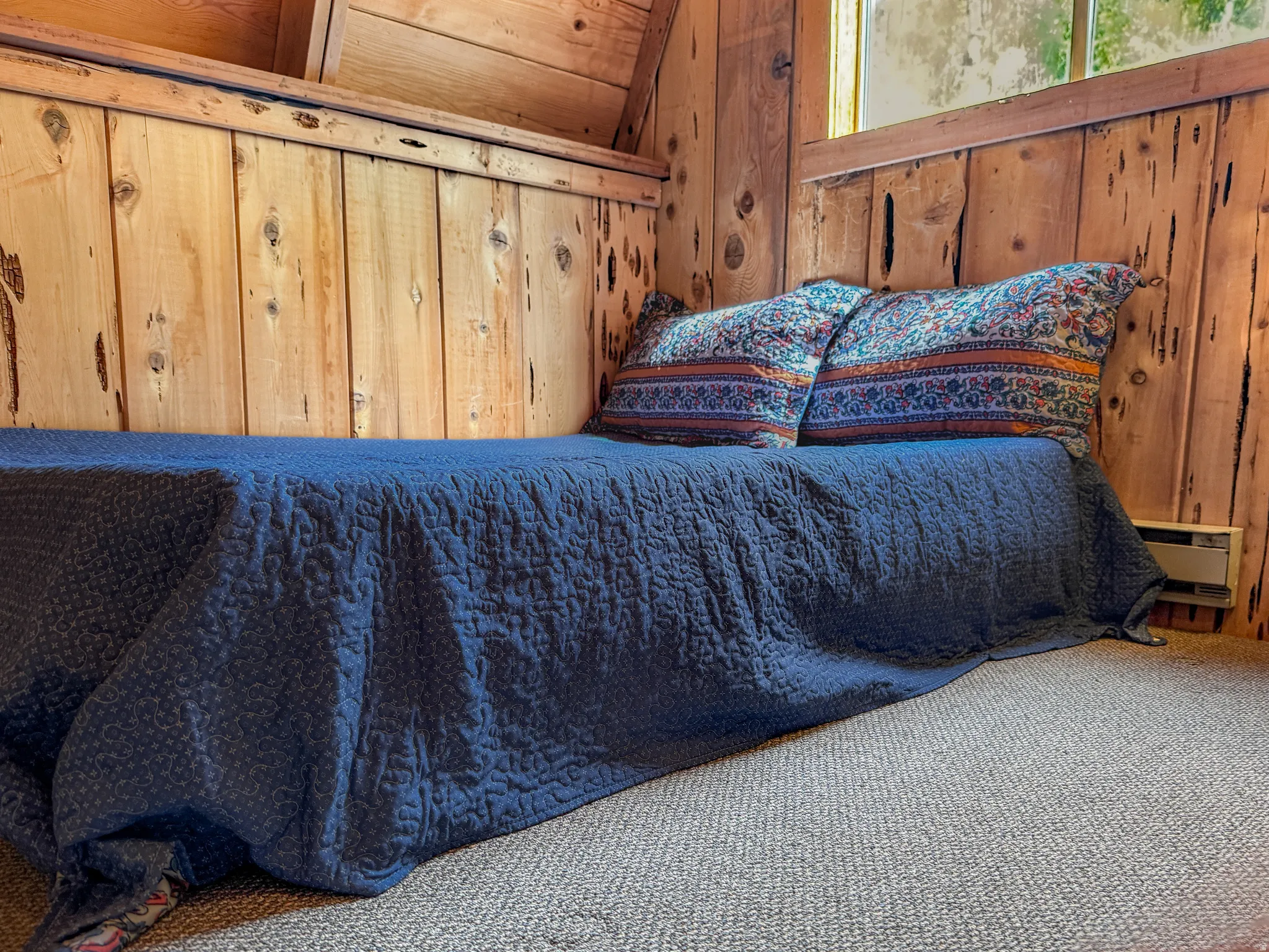Carpeted bedroom featuring wooden walls and vaulted ceiling