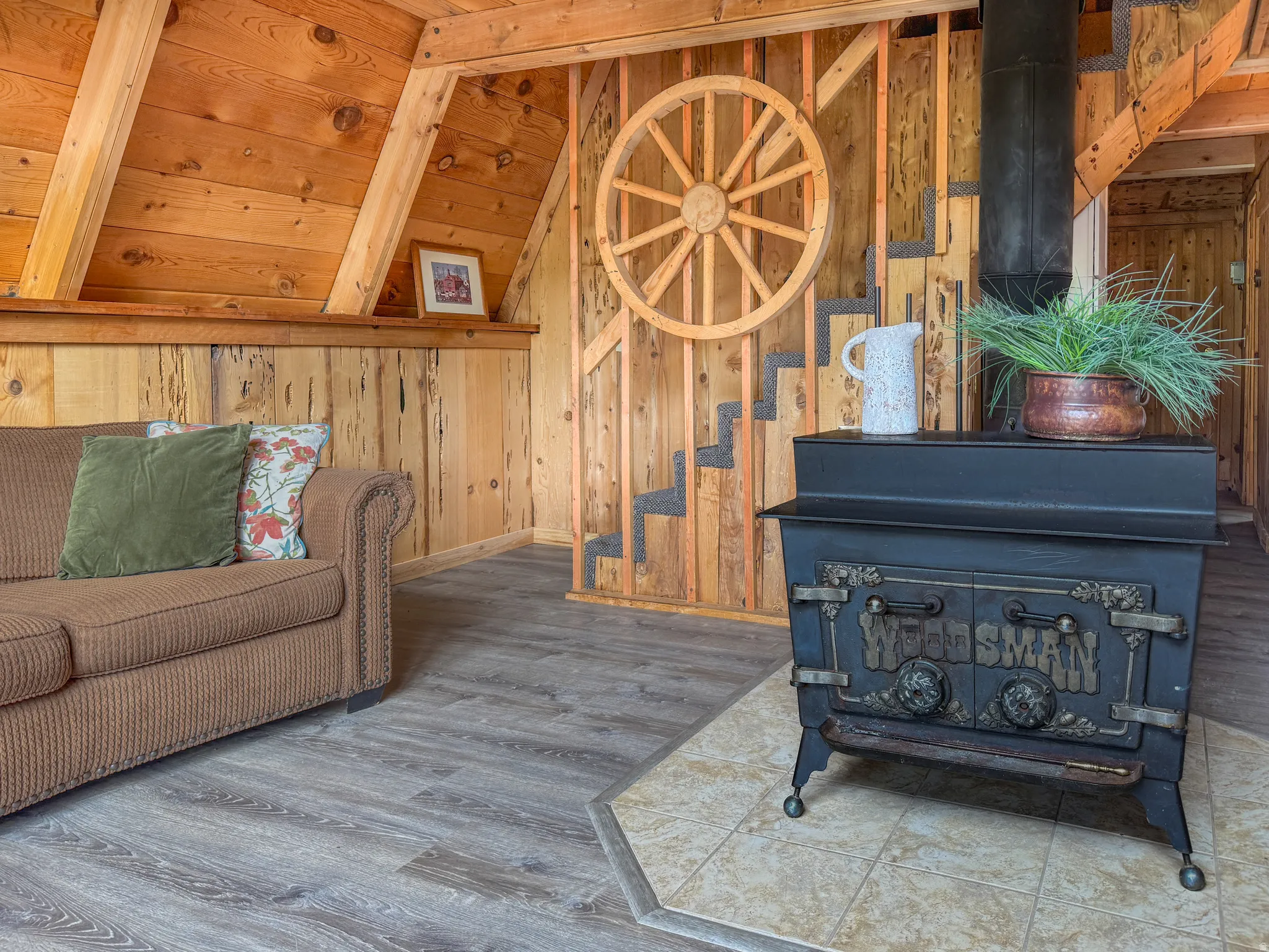 Living area featuring a wood stove, wood finished floors, vaulted ceiling, and wood walls