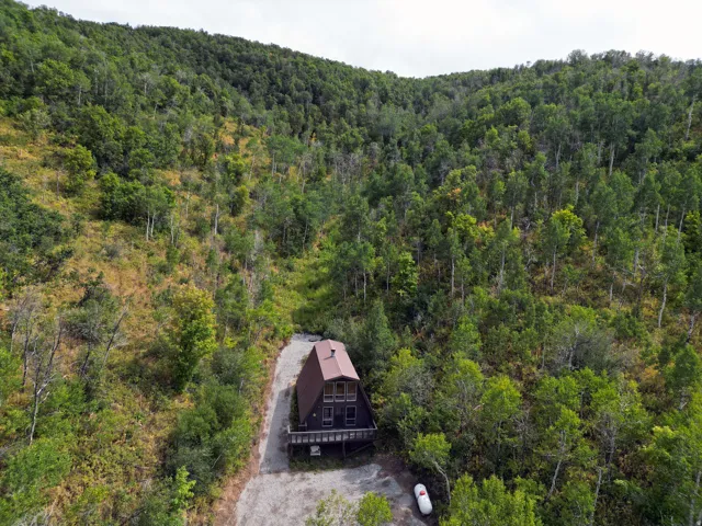 Aerial view of property and surrounding area with a heavily wooded area