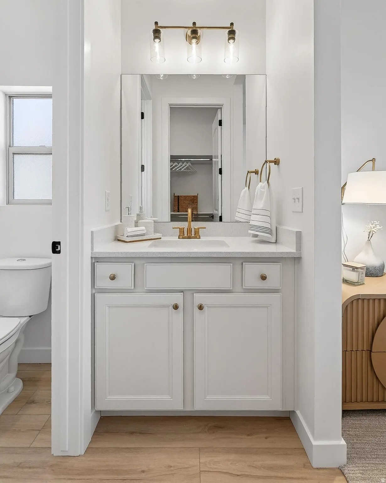 Full bath featuring vanity, light wood-type flooring, and a walk in closet