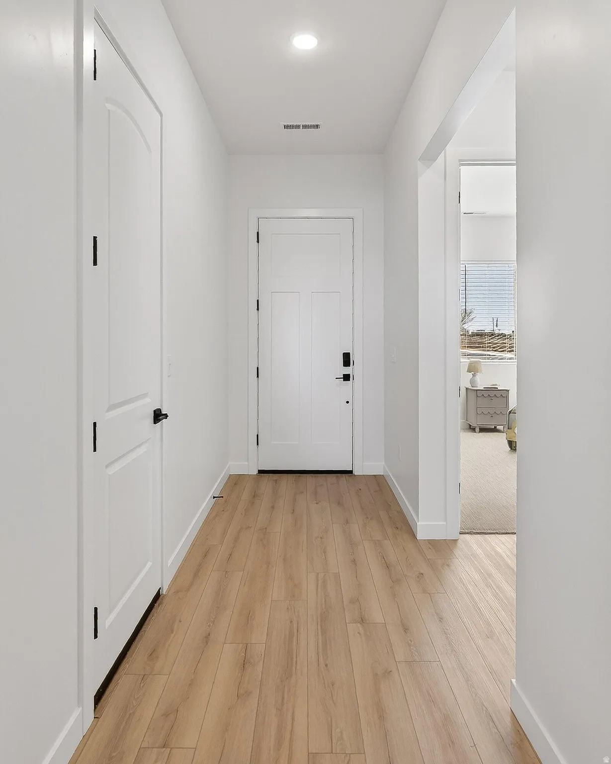 Corridor with light wood-type flooring and recessed lighting