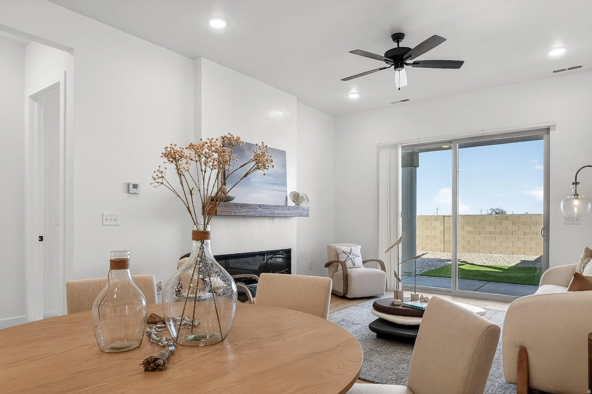 Living room with ceiling fan, a glass covered fireplace, recessed lighting, and wood finished floors