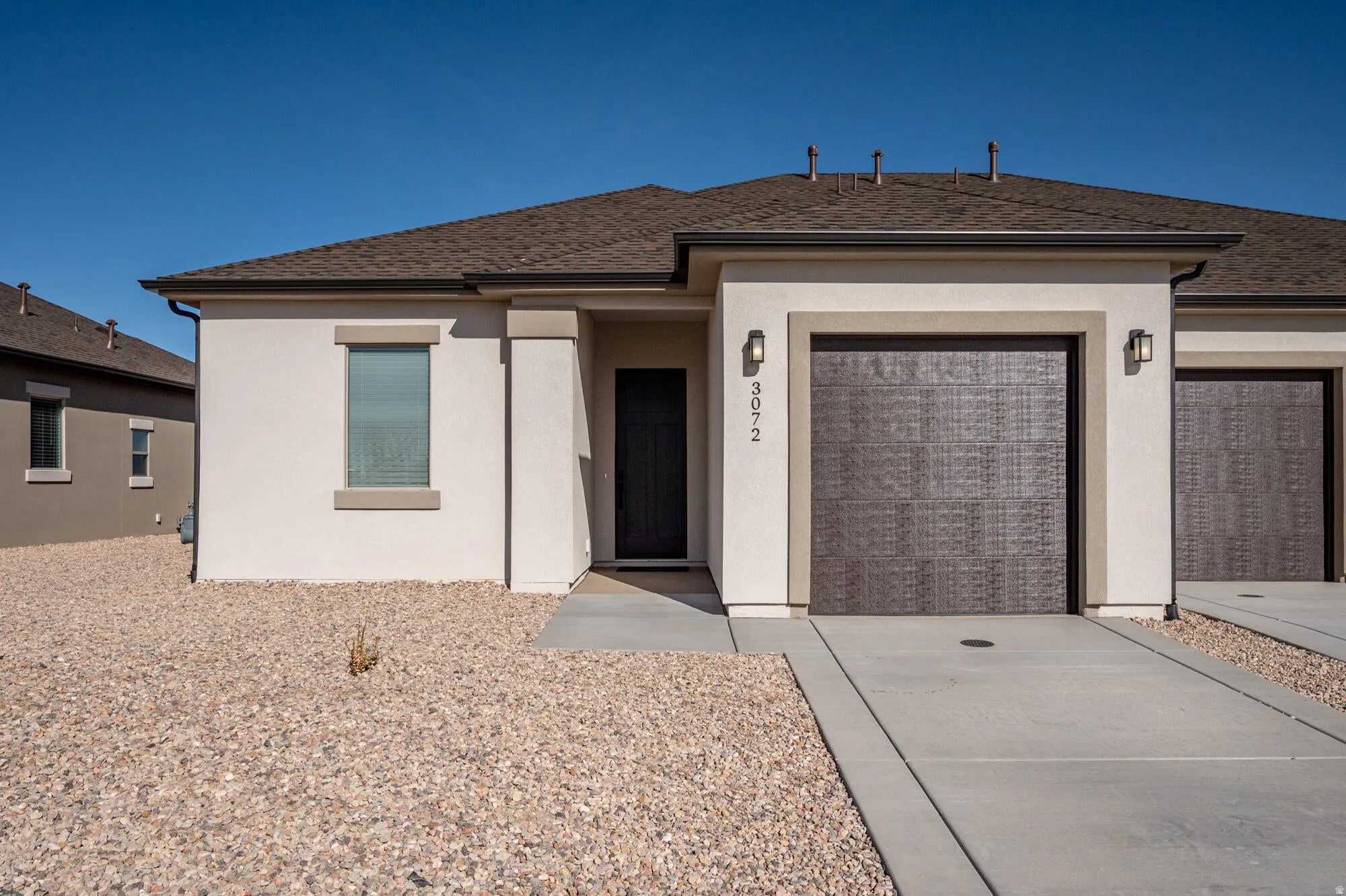 View of front facade featuring an attached garage, stucco siding, concrete driveway, and roof with shingles