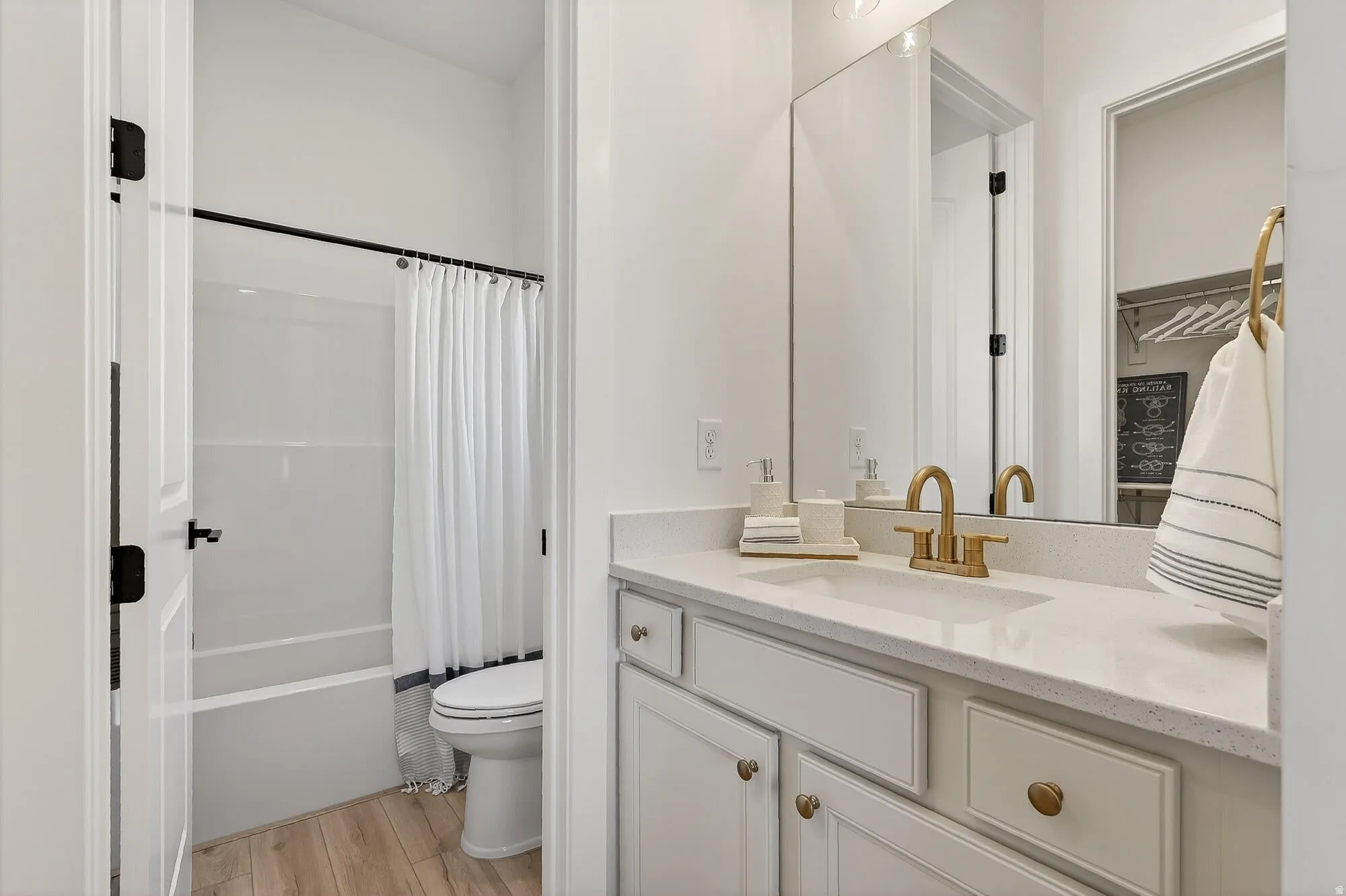 Full bath with vanity, light wood finished floors, and shower / bath combo